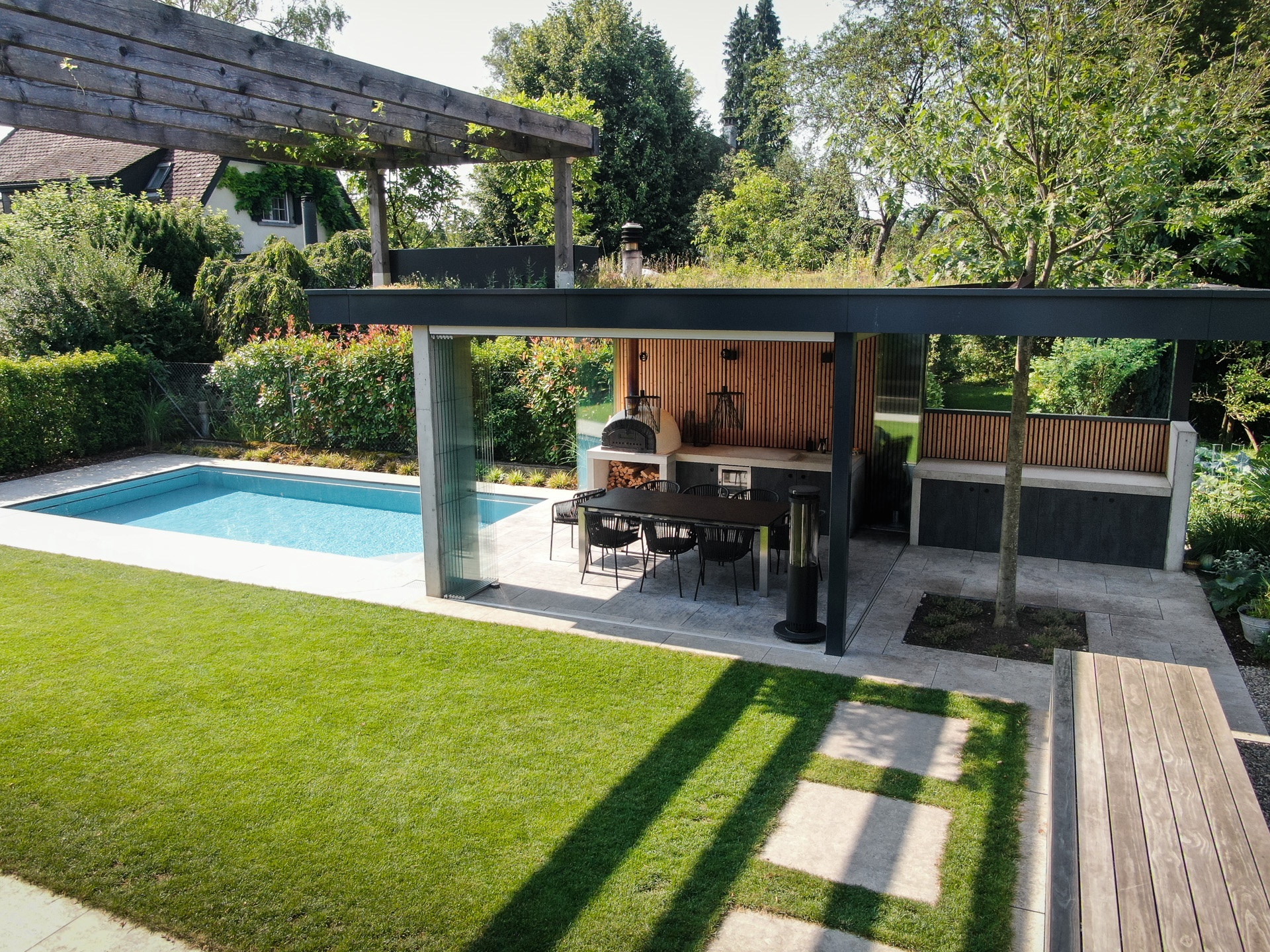 Garten mit Loggia, Swimmingpool und saftig grünem Rasen. 