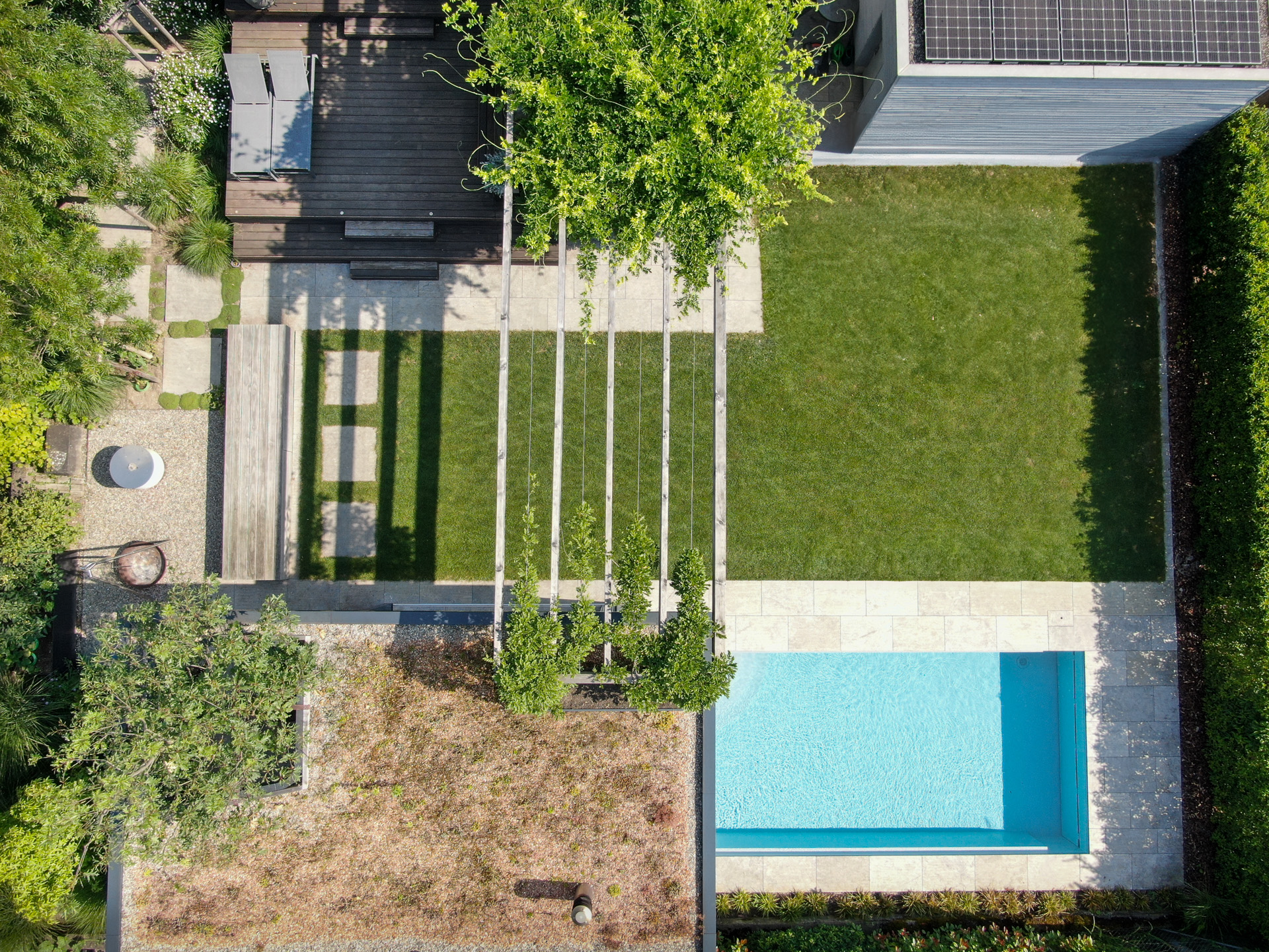 Vogelansicht eines Gartens mit Swimmingpool und Loggia. 