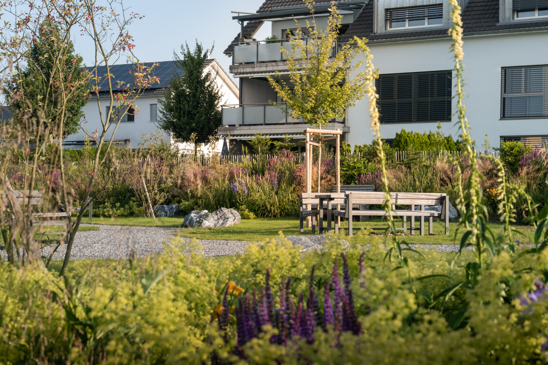 Wohnquartier mit Parkanlage, wunderschön blühende Blumenbeete und Kieswege.
