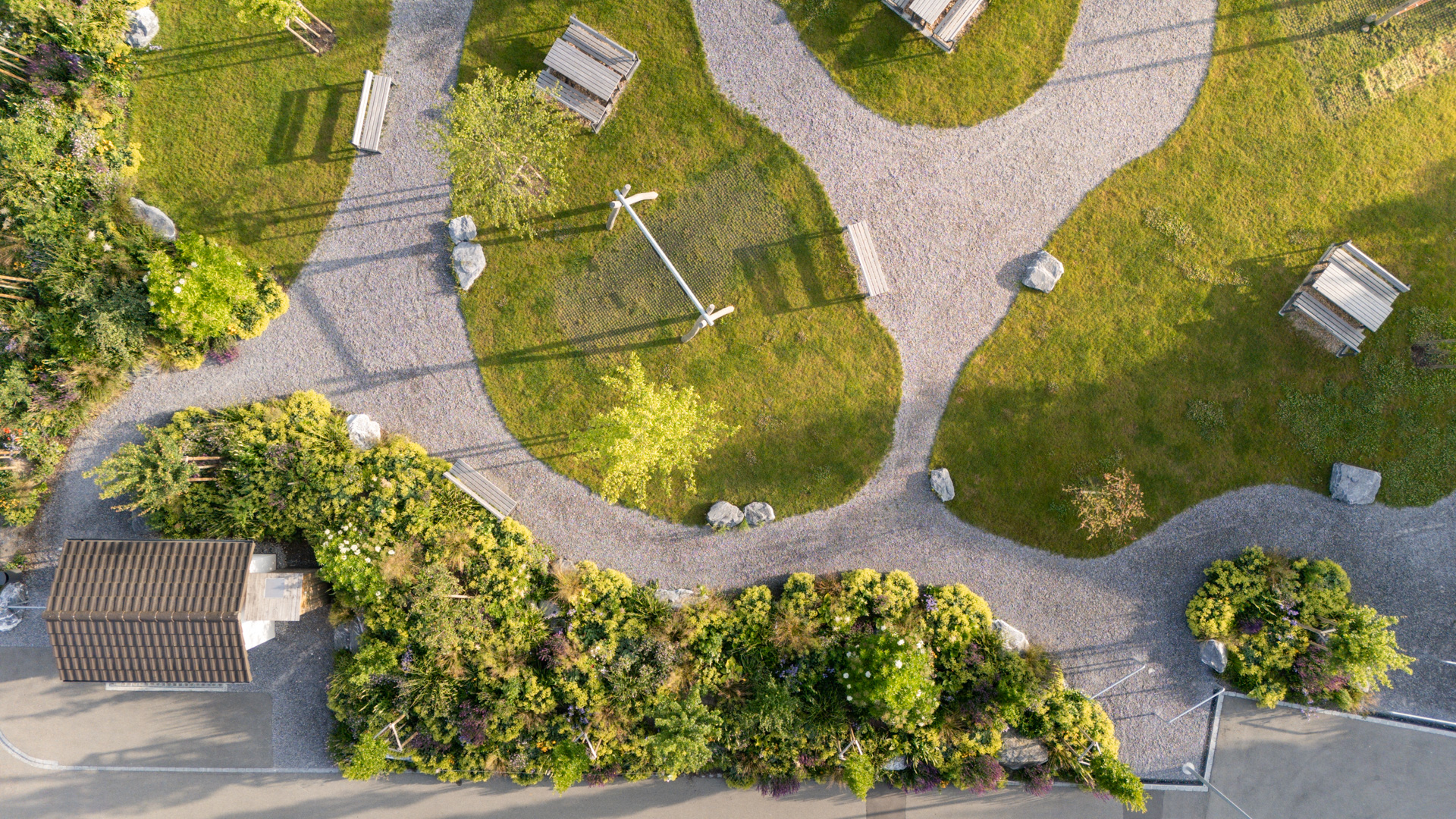 Übersicht in der Drohnenperspective eines Stadtparkes mit geschwungenen Kieswegen und prächtiger Bepflanzung.