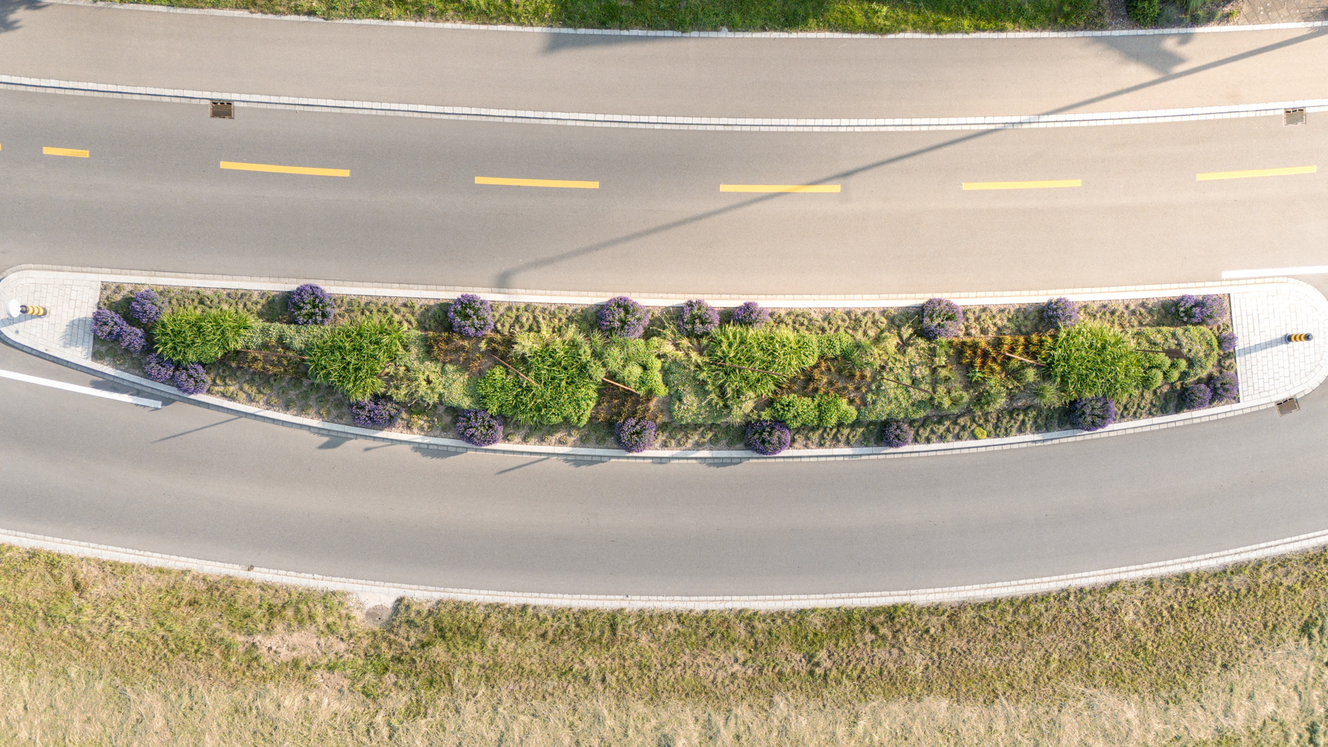 Drohnenansicht einer Hauptstrasse mit länglicher Verkehrsinsel im Ruderboot Look.