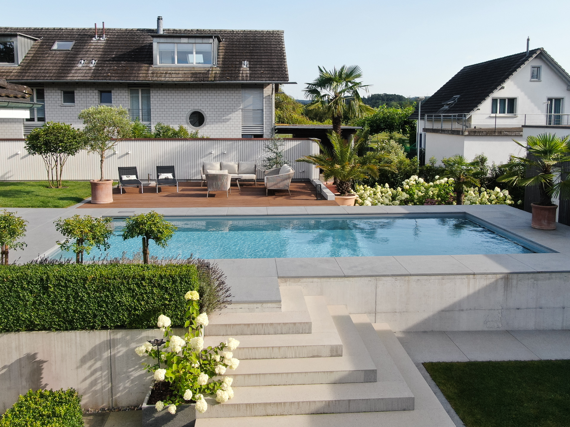 Terrassierter Garten mit Swimmingpool Garten Lounge und Palmen. 