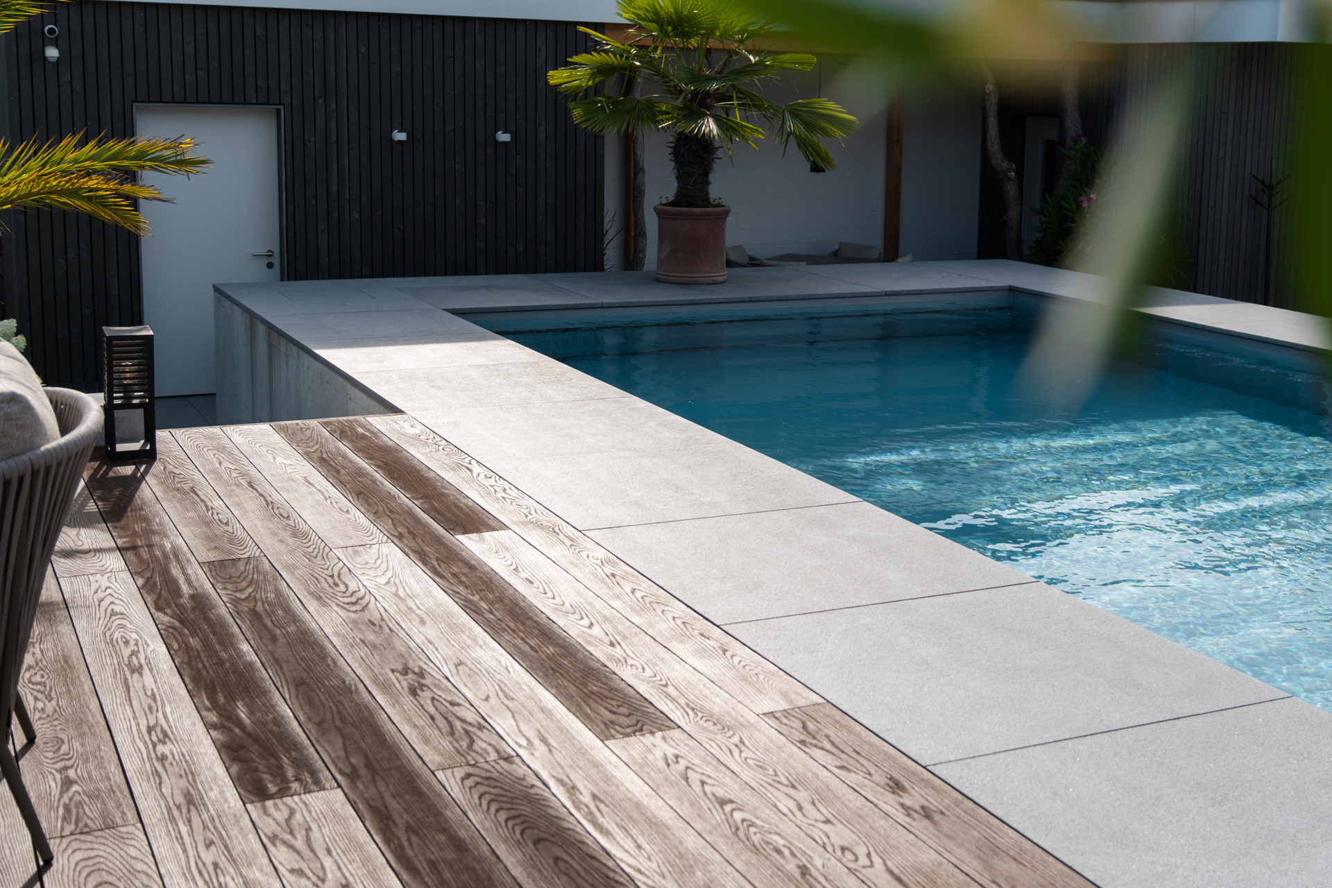 Holzrost neben einem Swimmingpool mit grossen Naturstein Platten. 