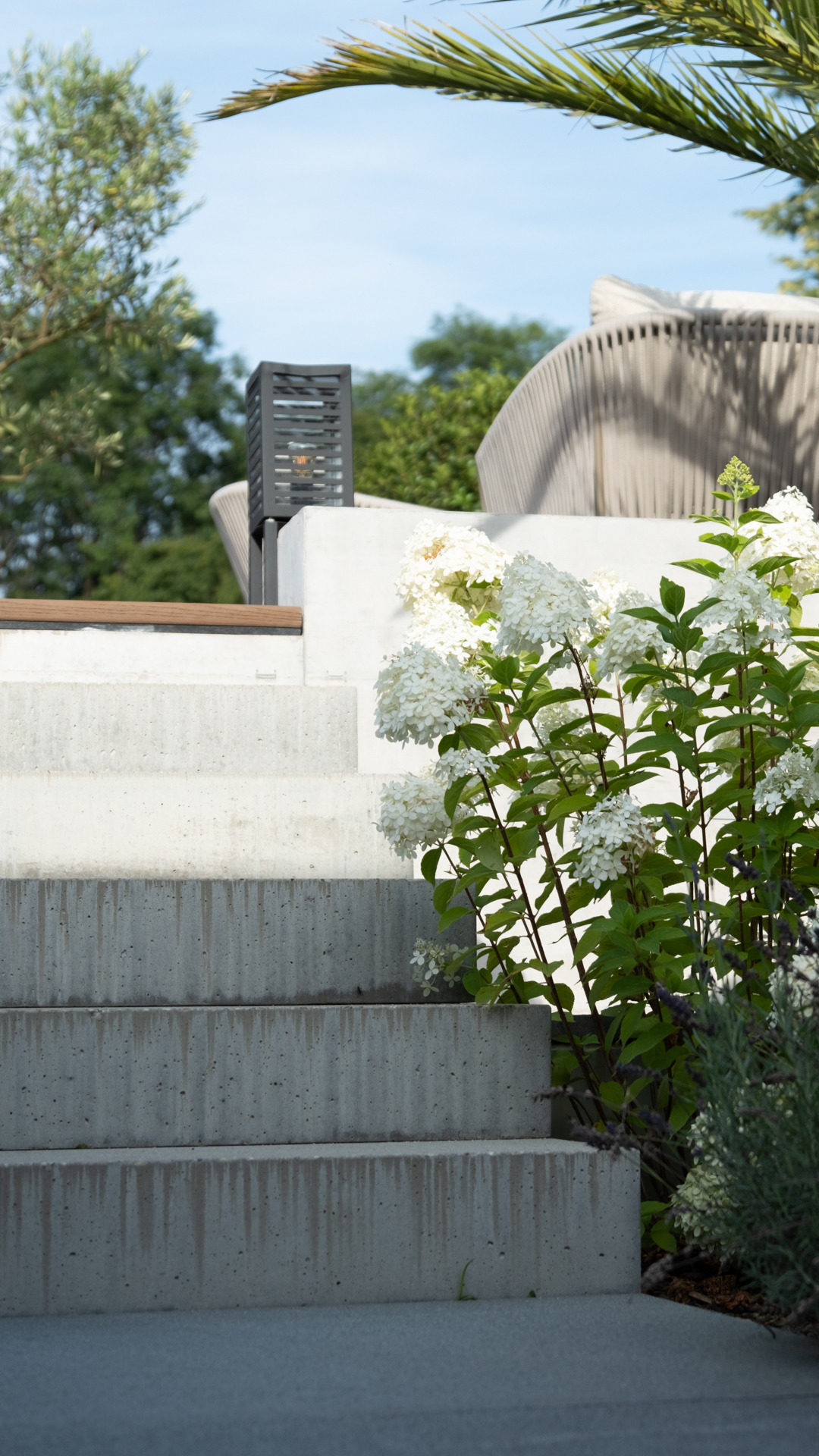 Beton Treppe mit Hortensien und Palmwedel. 