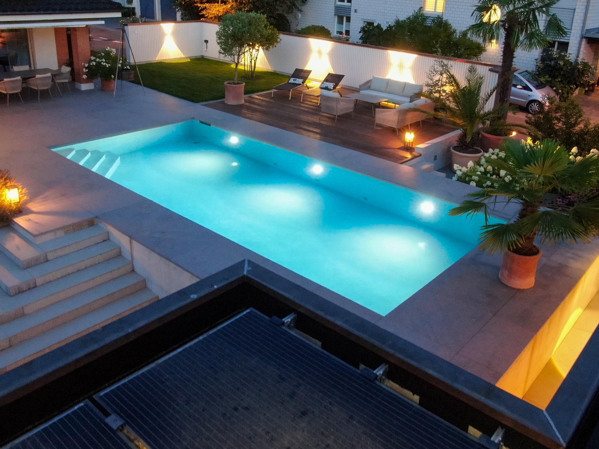 Drohen Ansicht eines Swimmingpooles bei Nacht mit gemütlich Sitzecke. 