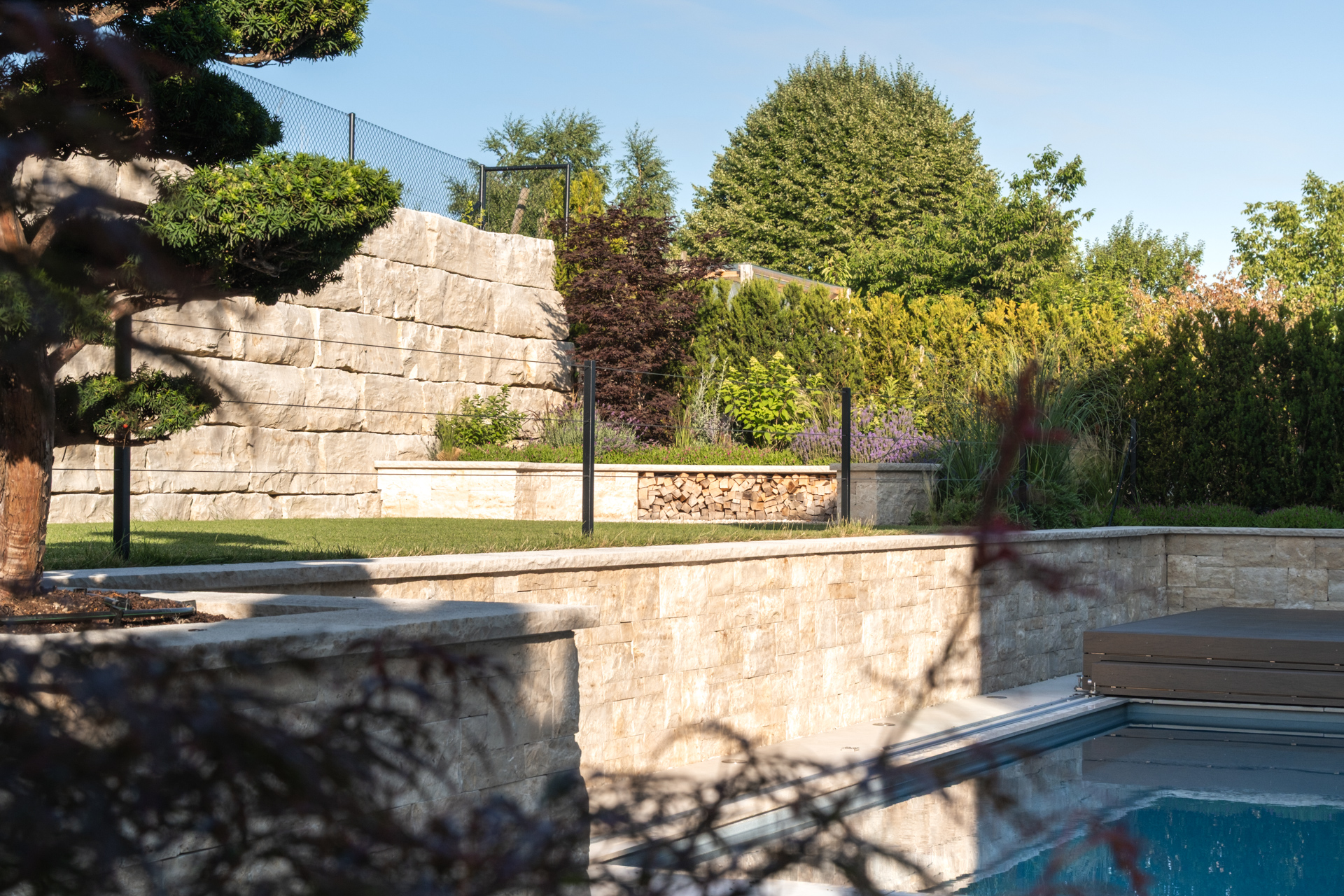 Mediterraner Garten mit warmen Naturstein viel Grün. 