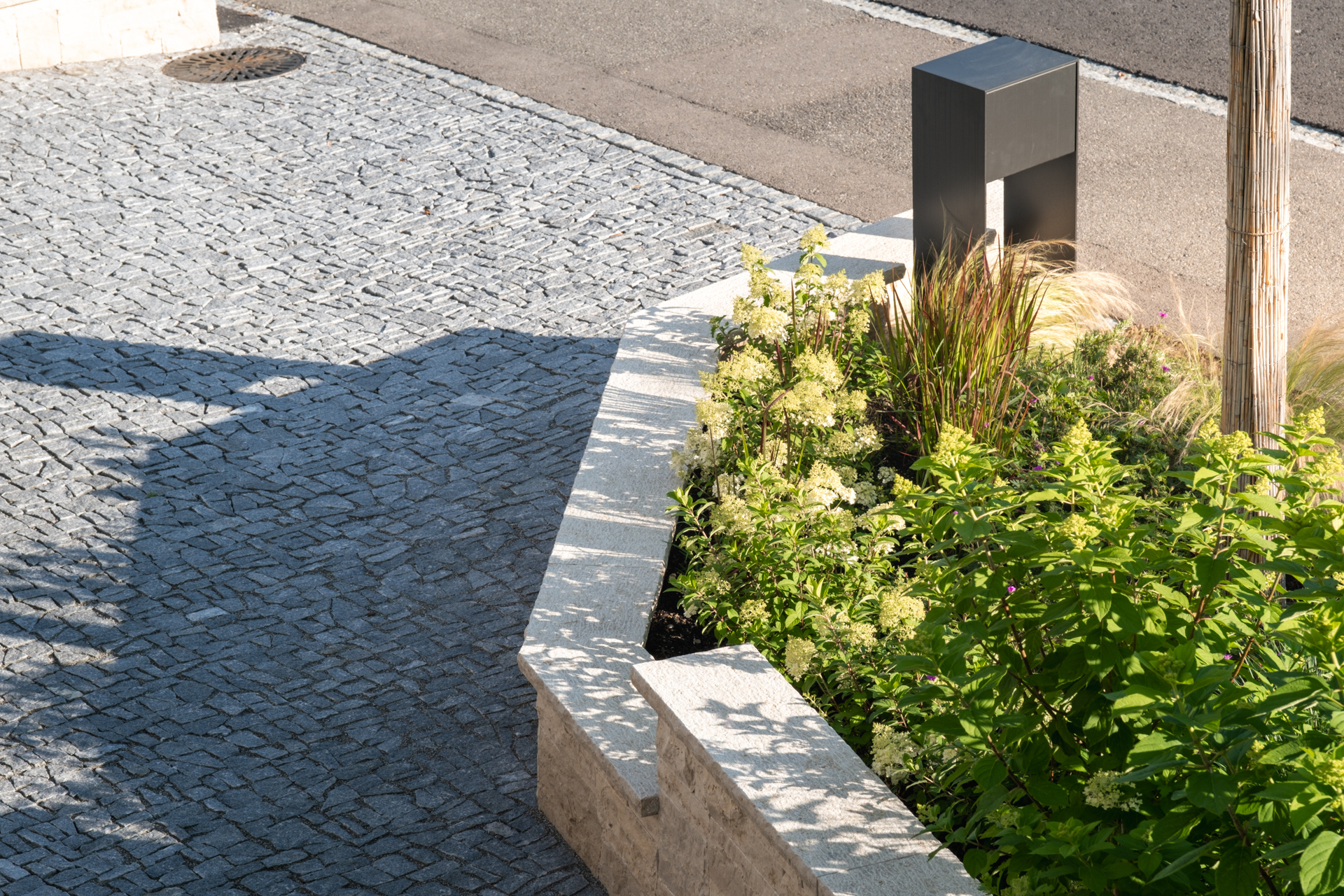 Blühende Stauden in einer Auffahrt mit Briefkasten. 