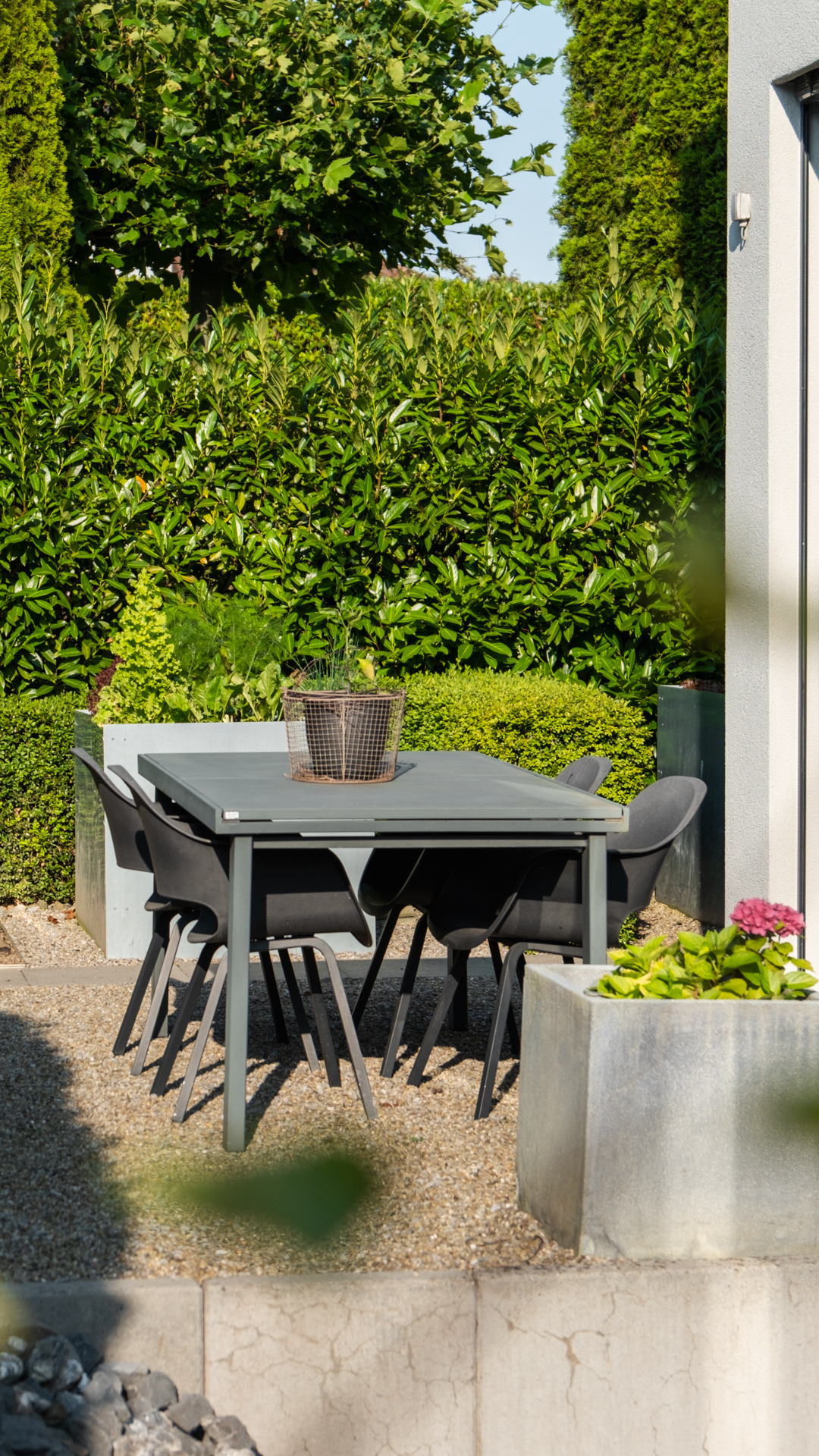 Kiesplatz im Garten mit Gartenmöbeln im Hintergrund eine hohe blickdichte Hecke. 