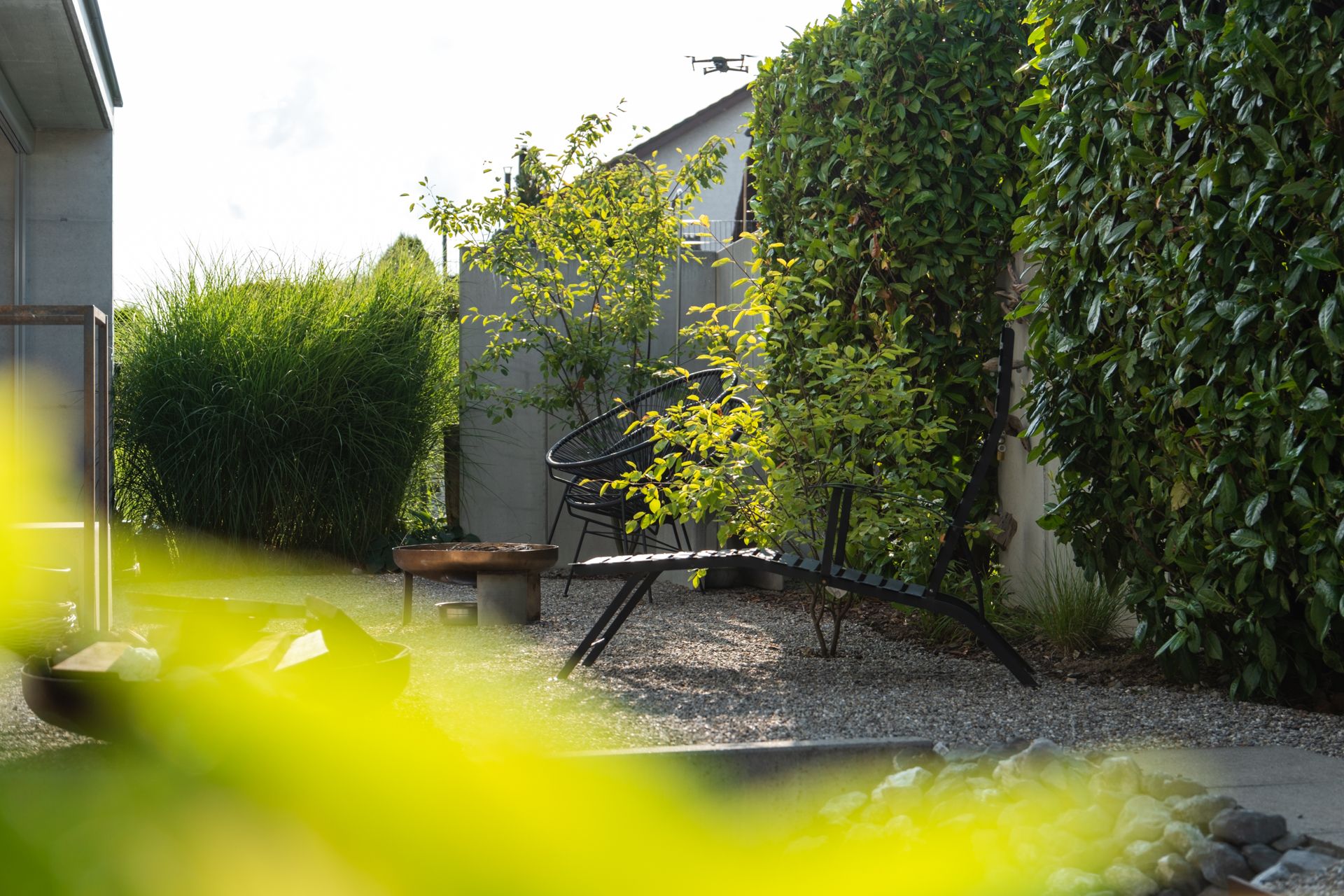 Moderner Kiesplatz Garten mit Rattanmöbeln und Feuerschale. 