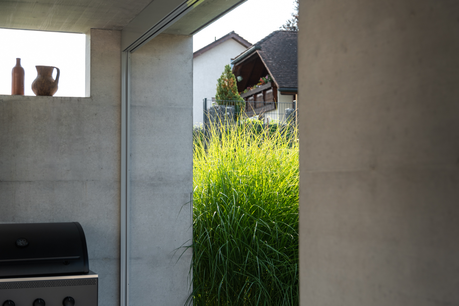 Beton Loggia mit hohen Gräsern in privatem Garten. 