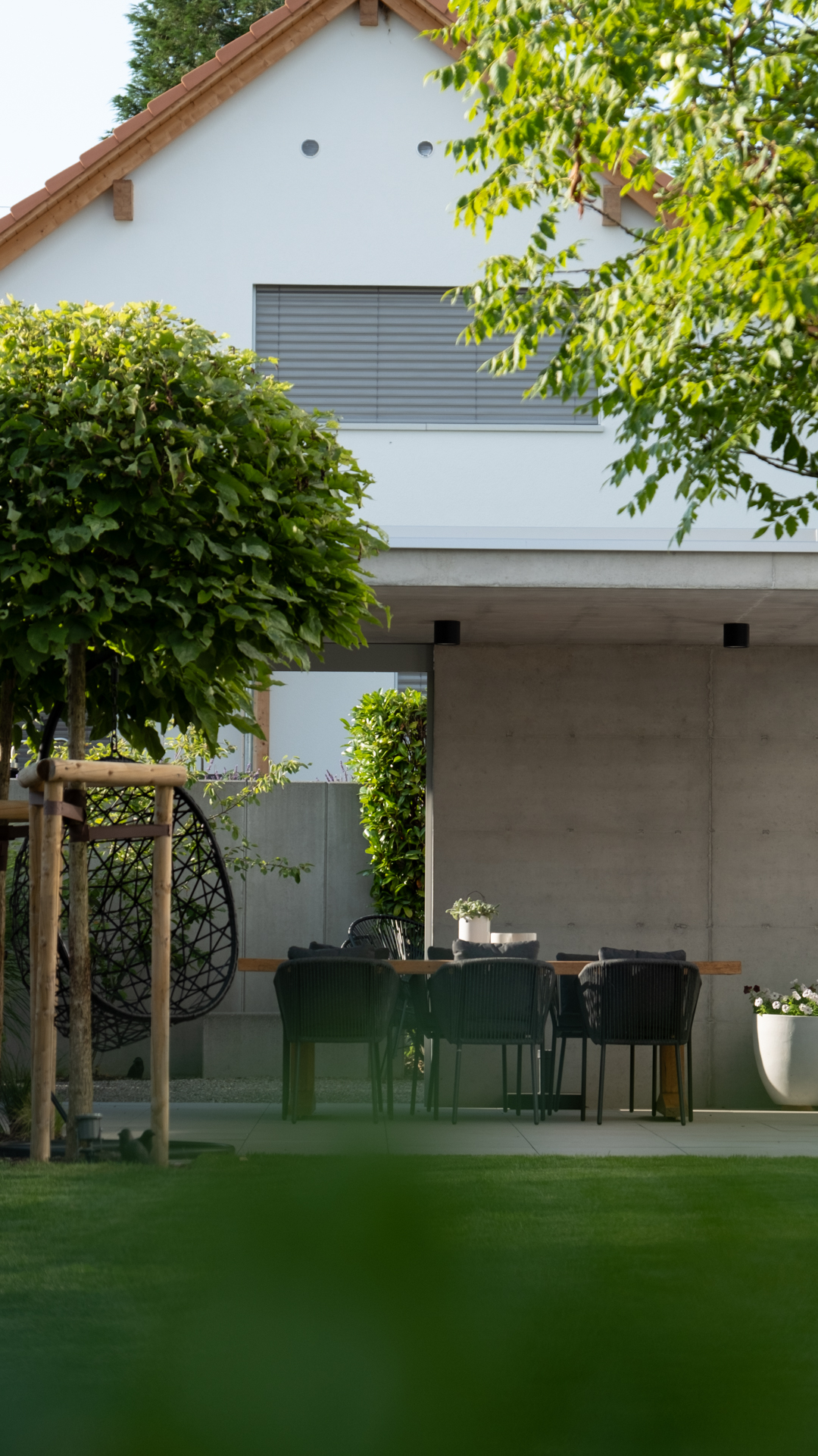 Schöne Beton Loggia in Wohnquartier mit hohen runden Bäumen und grosser Rasenfläche. 