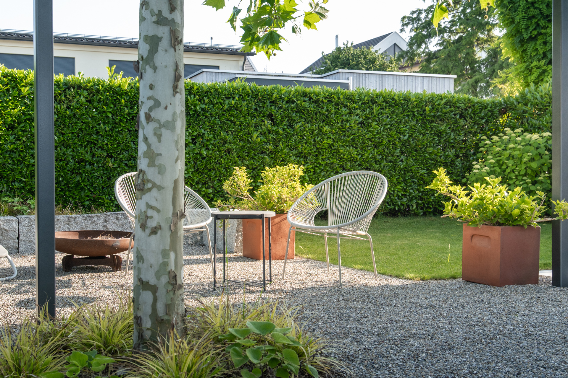 Kiesgarten mit hochwertigen weissen Korbmöbeln und hochstämmigen Birken. 