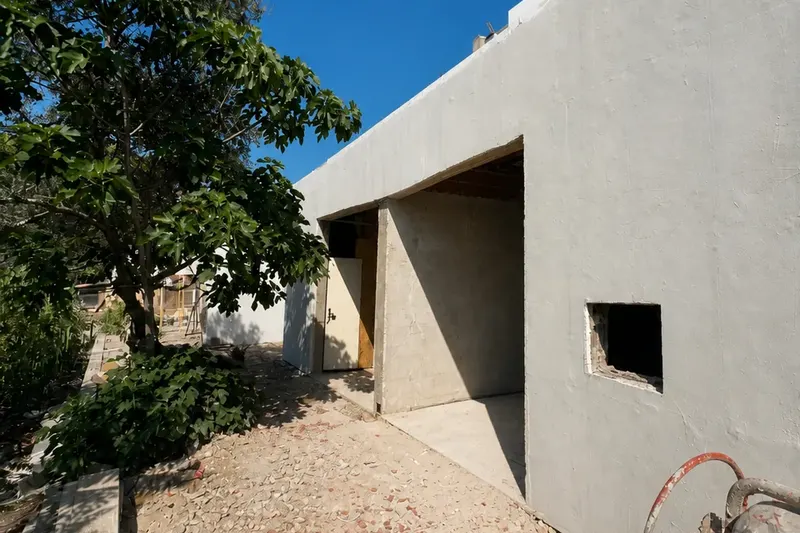 Fachada em obra nas Amoreiras, com paredes claras, vãos abertos e pátio.