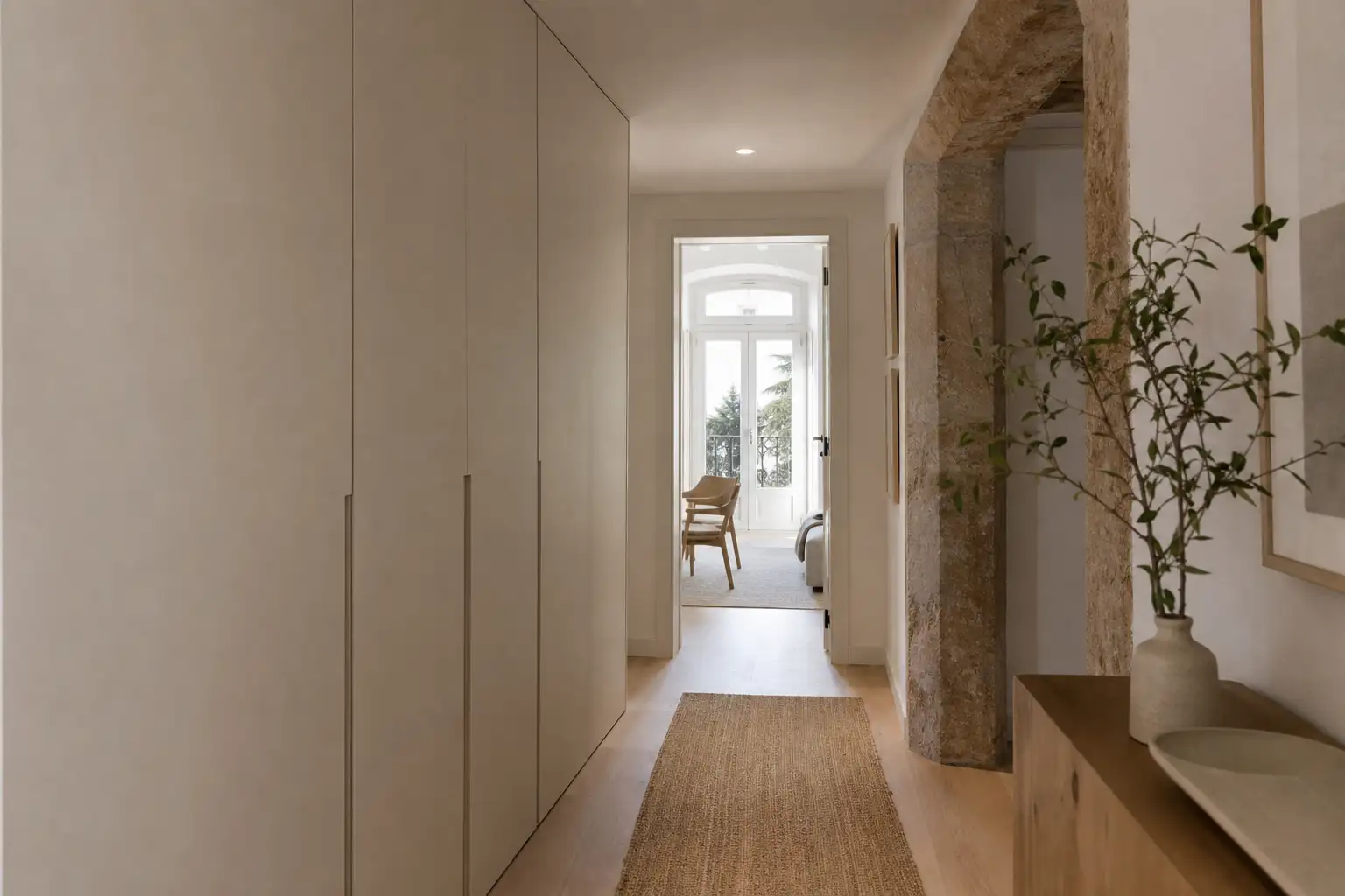 Corredor de apartamento remodelado com arrumação embutida discreta e portas do chão ao teto.