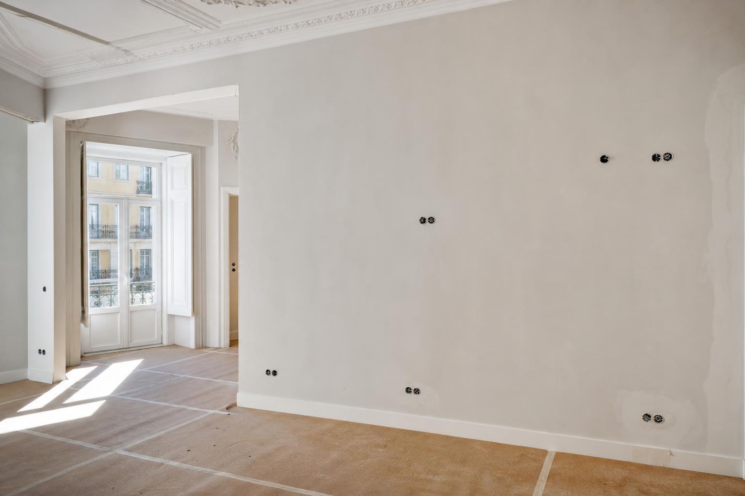 Parede de apartamento em remodelação com marcações organizadas para tomadas e interruptores.