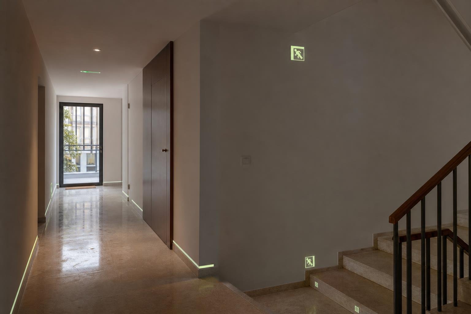 Residential building corridor with discreet photoluminescent signage near a stairway