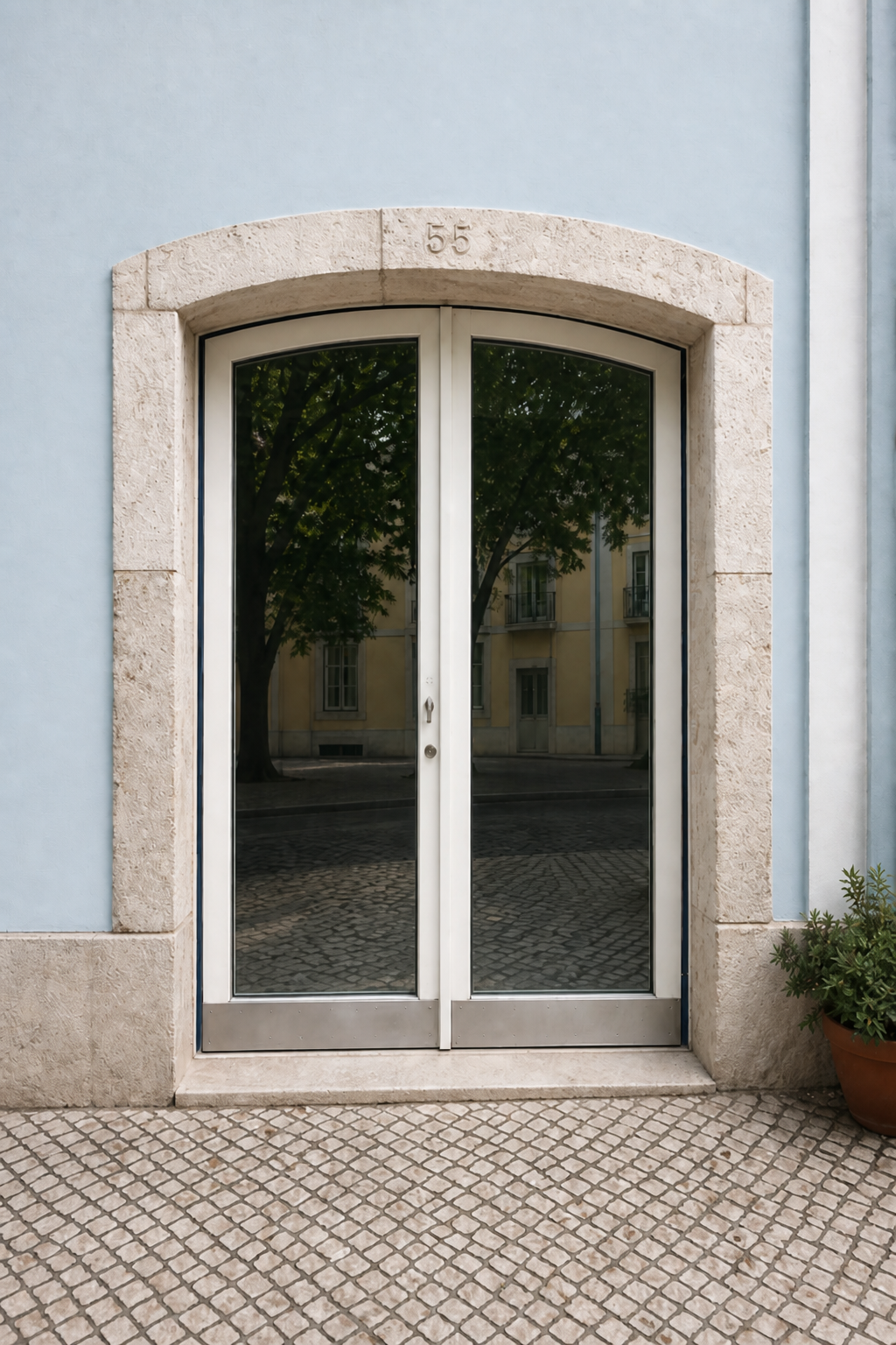 Antes: entrada de loja com porta envidraçada branca, moldura de pedra e fachada azul-clara