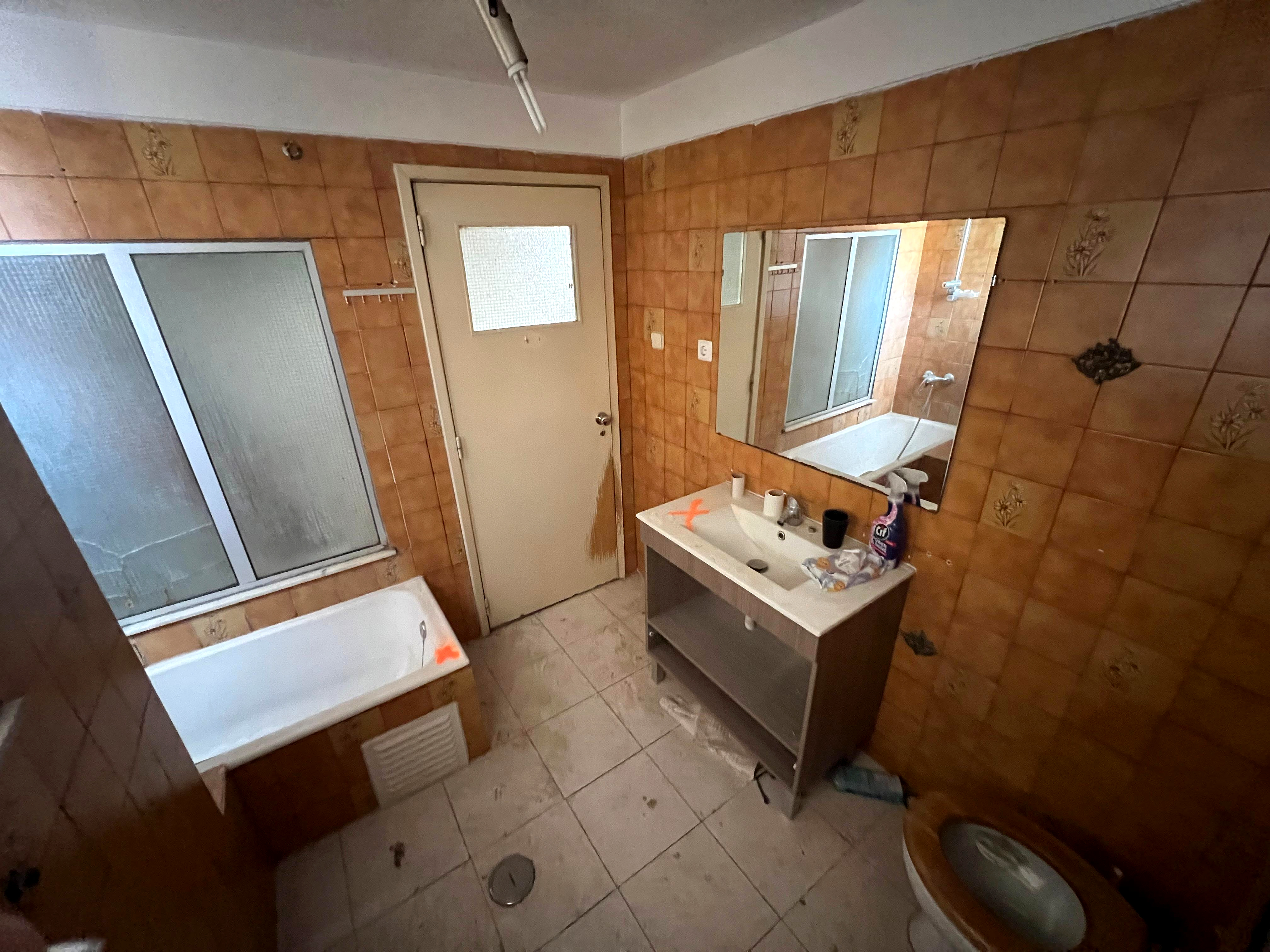 Antes: casa de banho datada com azulejos castanhos, banheira e lavatório suspenso