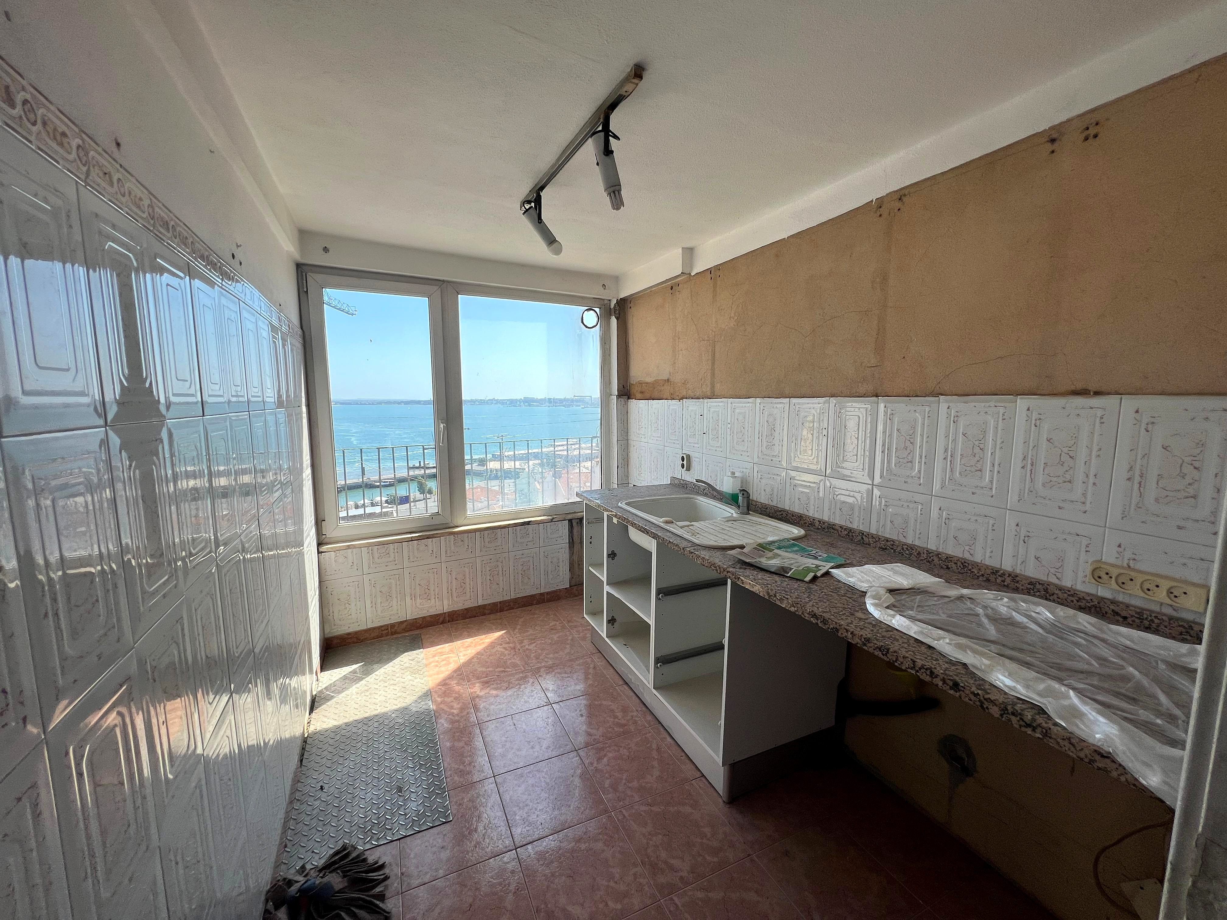 Antes: cozinha datada com azulejos decorativos, bancada em pedra e vista para o Tejo