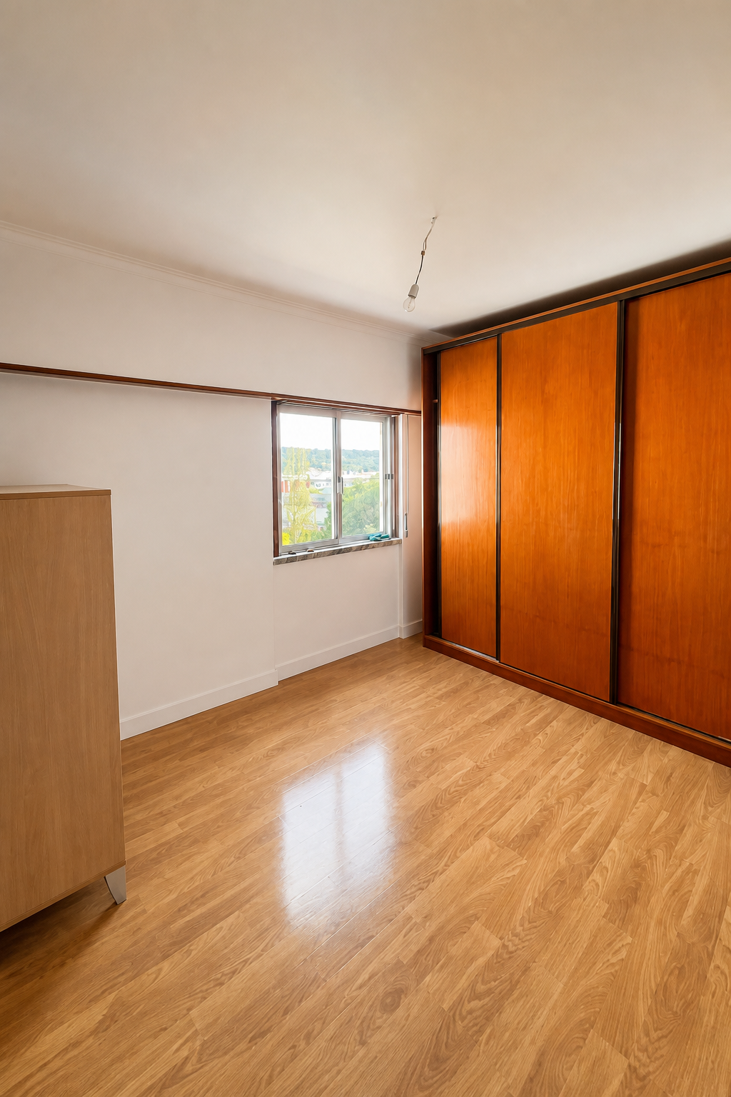 Depois: quarto renovado com pavimento em madeira, paredes claras e roupeiro em madeira