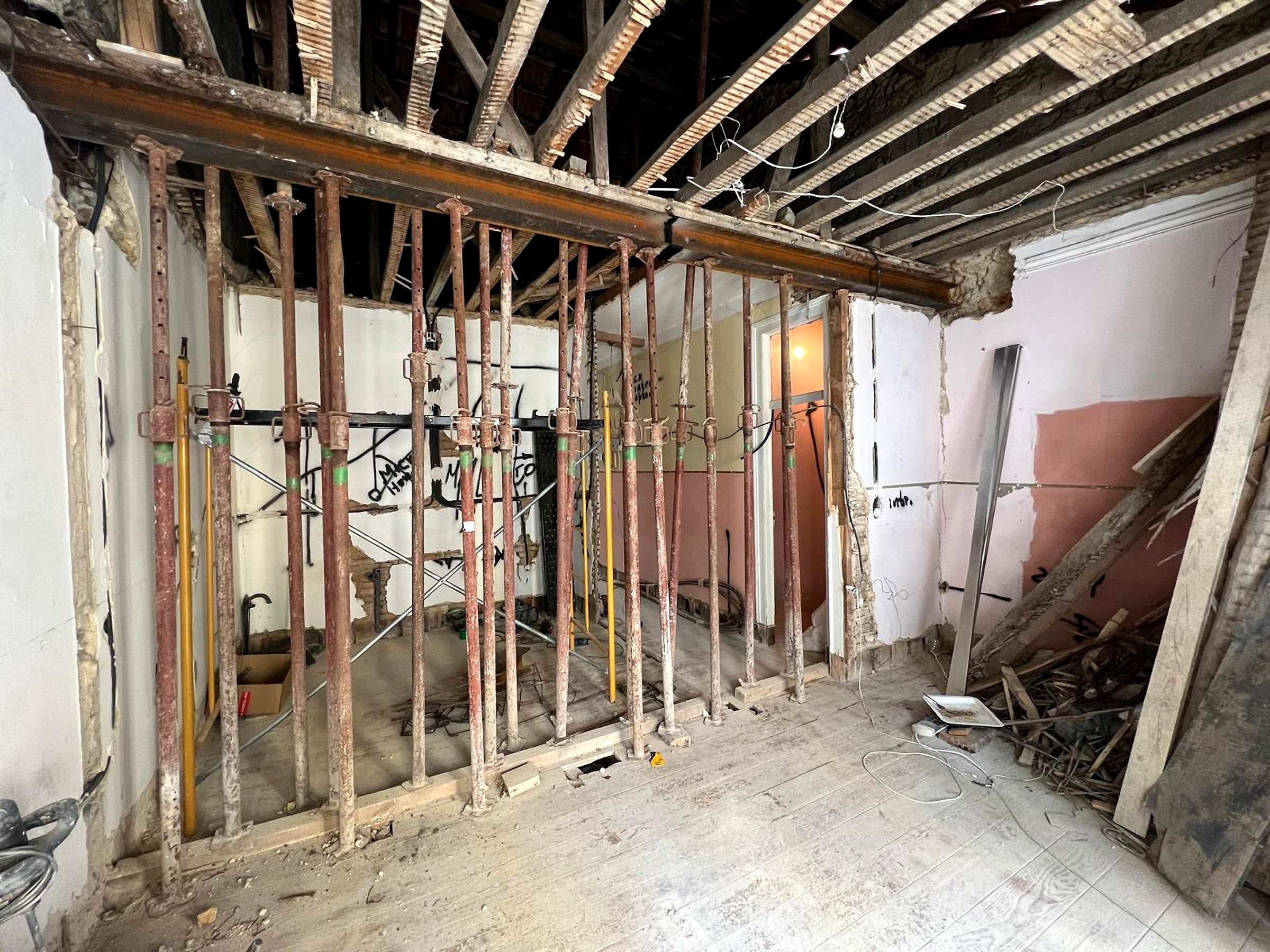 Antes: espaço em obra com escoramentos metálicos, teto aberto e paredes parcialmente demolidas