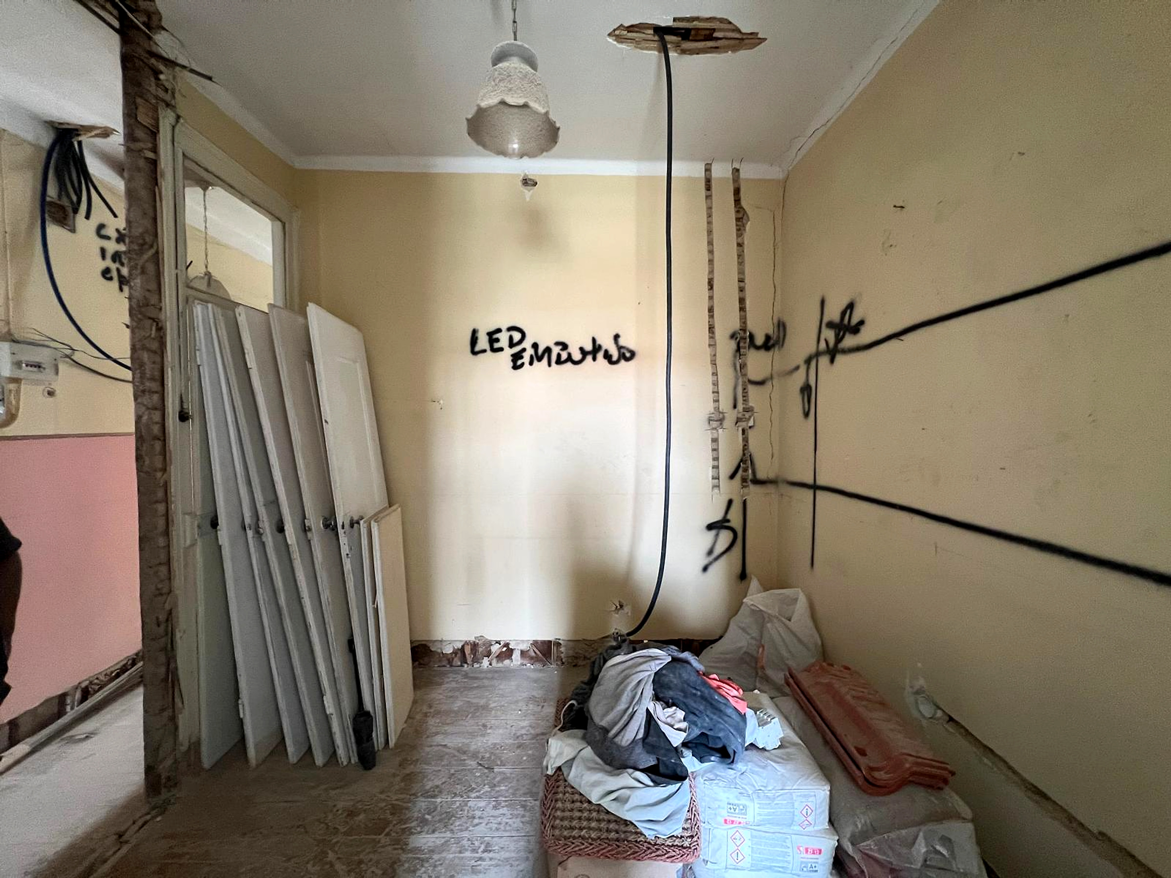 Antes: divisão em demolição com cabos pendentes, portas removidas e materiais de obra
