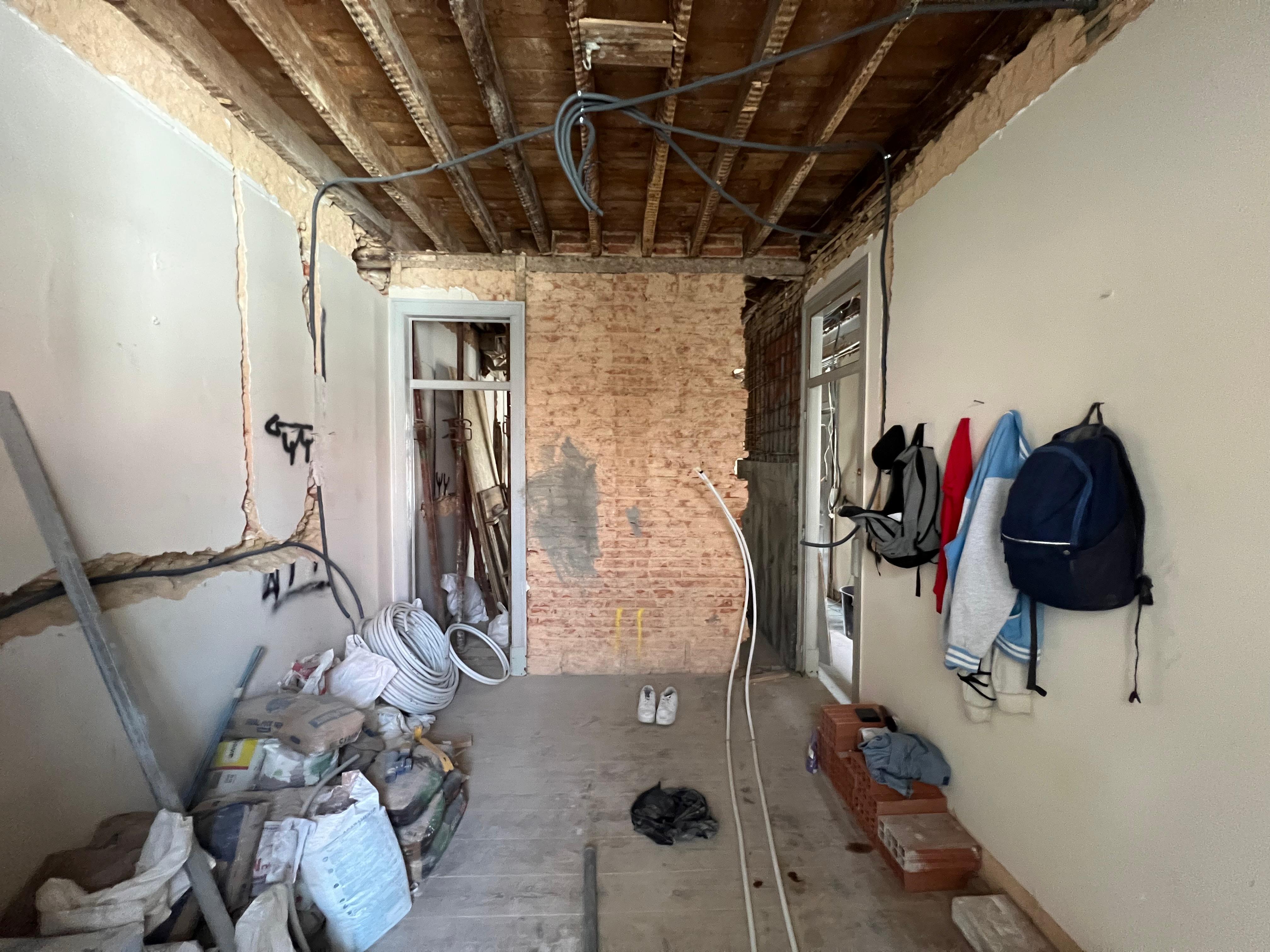 Antes: corredor em obra com teto de madeira exposto, parede de tijolo e cablagem suspensa