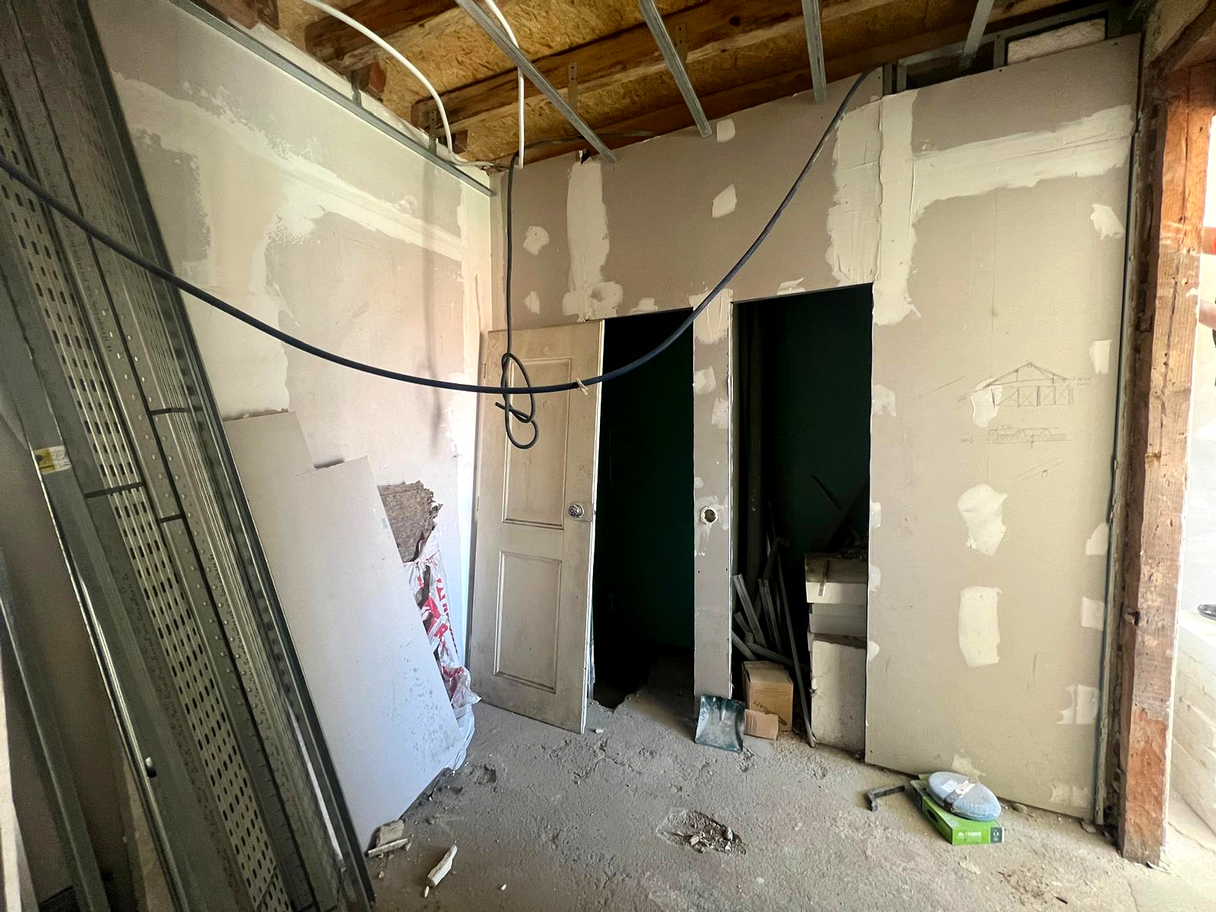 Antes: compartimento em obra com divisórias em gesso cartonado, portas removidas e cabos expostos