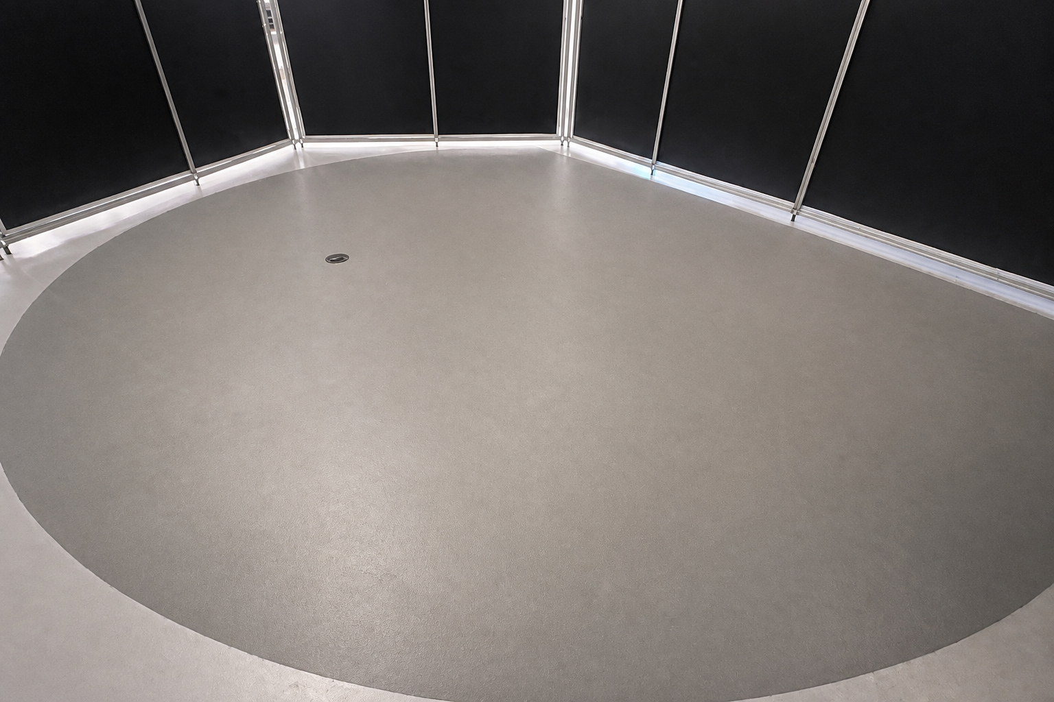 Intervenção no Museu MAAT: pavimento circular cinzento junto a painéis pretos e perfis metálicos