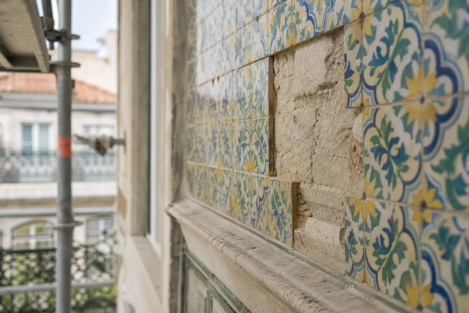 Pormenor de azulejos e argamassa numa fachada lisboeta durante uma intervenção de conservação