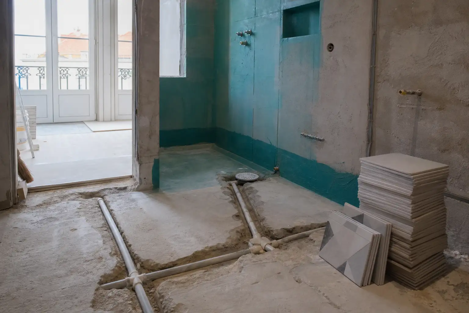 Technical preparation of floor and plumbing for installing a shower tray during renovation.