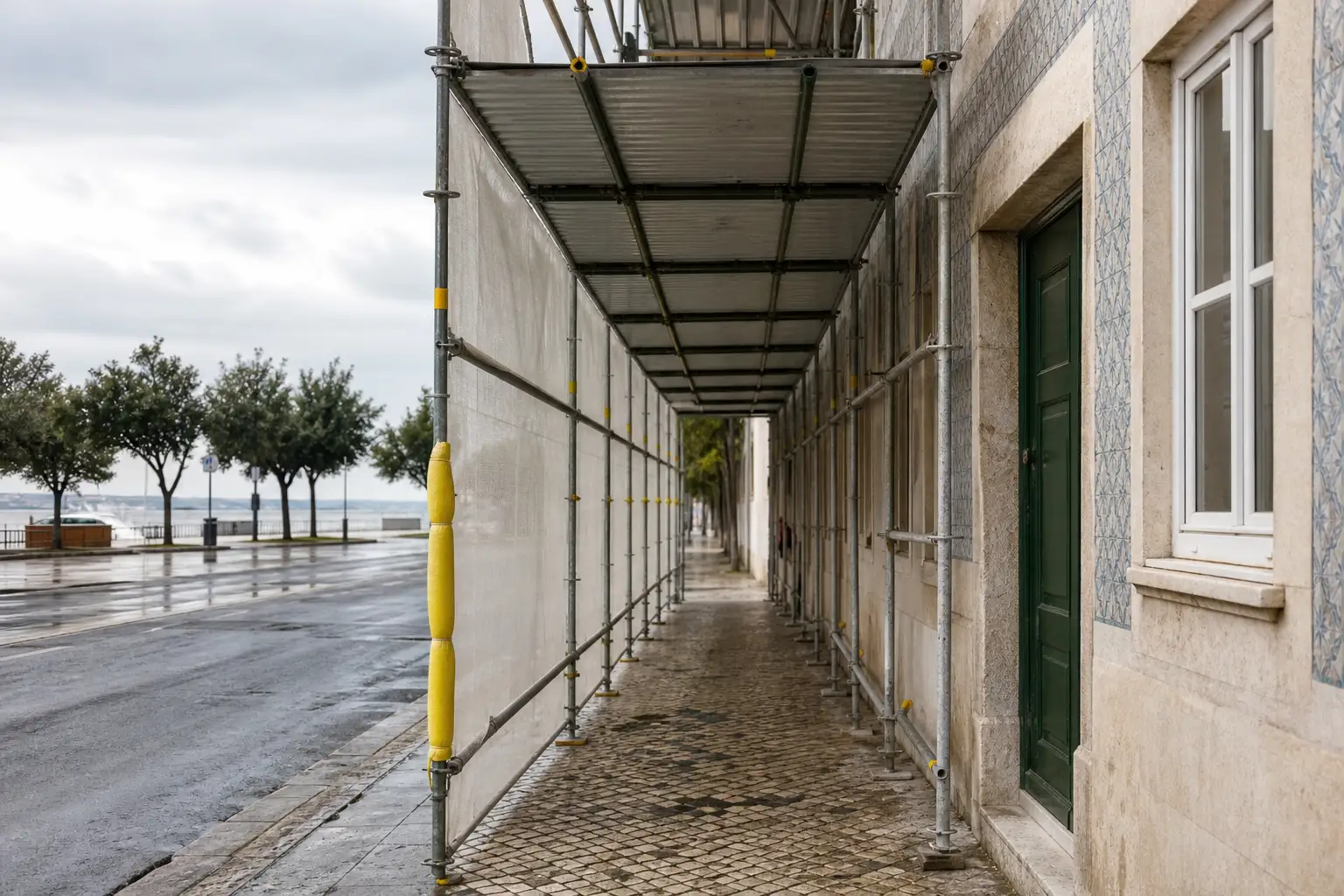 Pormenor de andaime junto a fachada lisboeta com percurso pedonal medido e pala de proteção