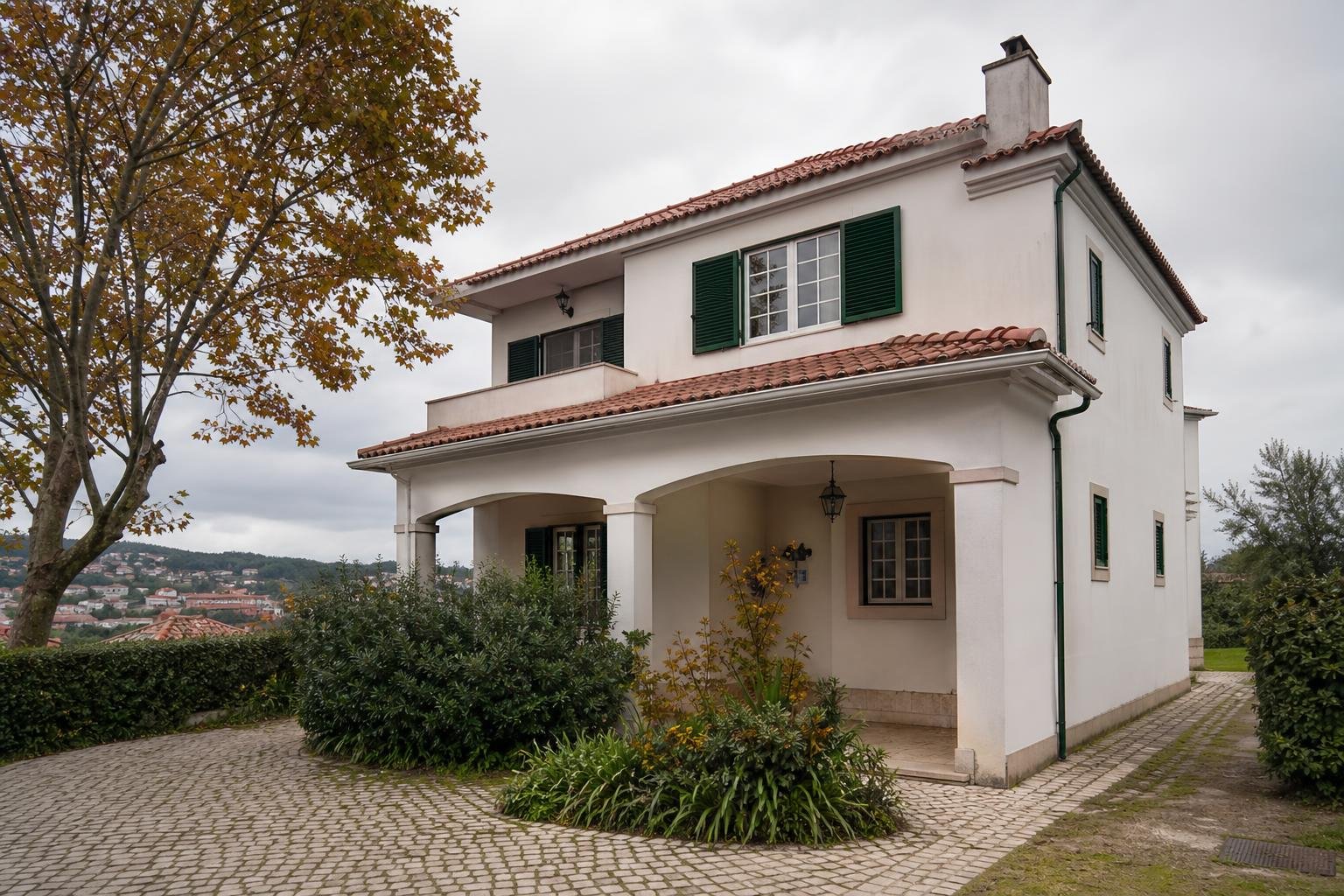 Lisbon-area detached house with tiled roof, gutters and downpipe prepared for autumn rain.