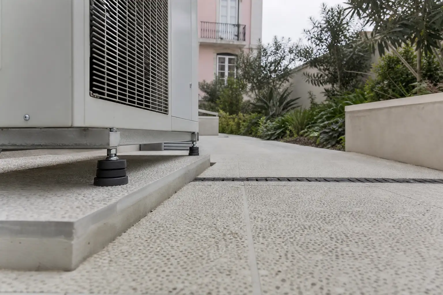 Close view of non-slip exterior paving with drainage and anti-vibration mounts in a garden technical area.