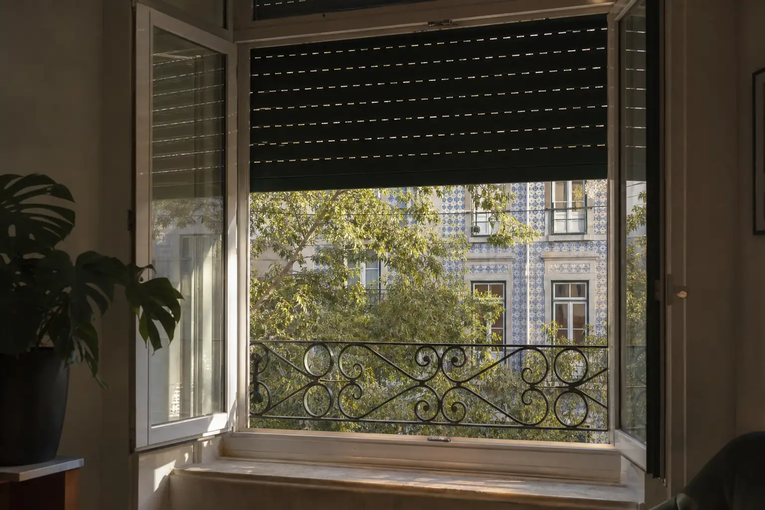 Janela de apartamento em Lisboa ao início da manhã, com sombreamento regulável e ventilação para arrefecer a casa.