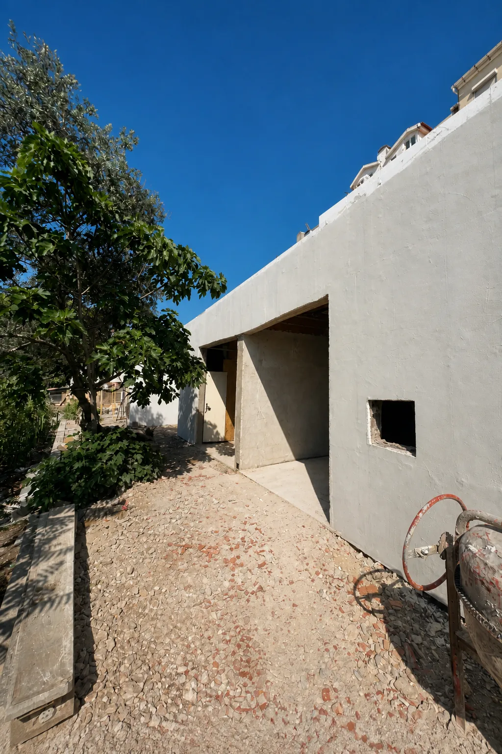 Fachada em obra nas Amoreiras, com paredes claras, vãos abertos e uma betoneira no espaço exterior.