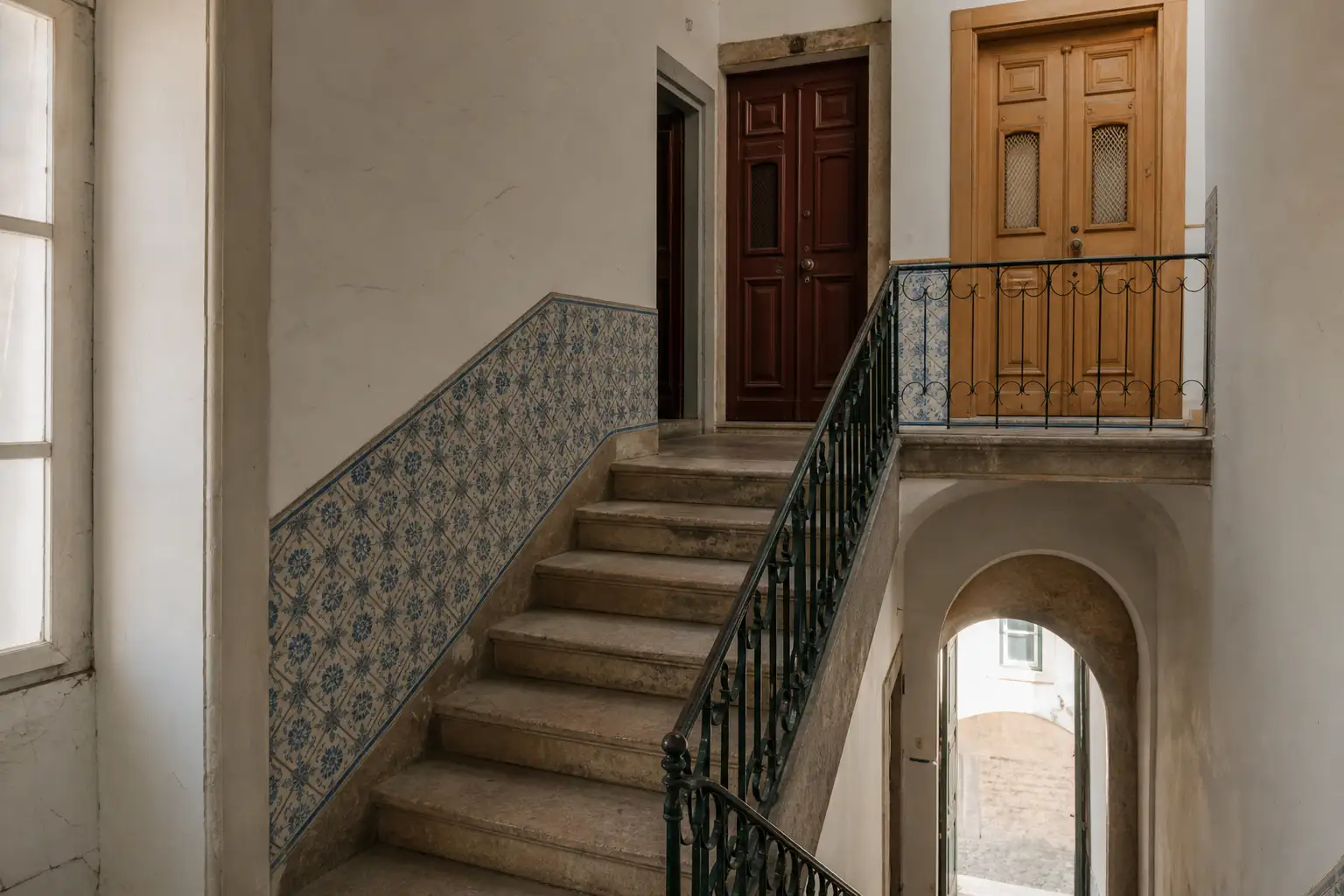 Escadaria de prédio antigo em Lisboa com portas de diferentes pisos, ilustrando espaços e acessos partilhados