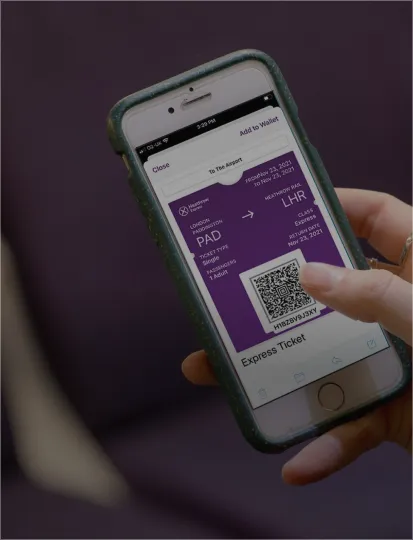 A close-up of a hand with a phone showing a QR code, highlighting the Heathrow app on the device.