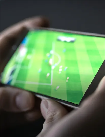 A person’s hands holding a mobile phone displaying a live football game on the screen.