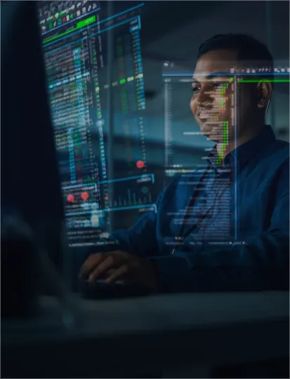 IT engineer performing code and infrastructure audit on multiple screens in a modern office, showcasing software development and system performance monitoring.
