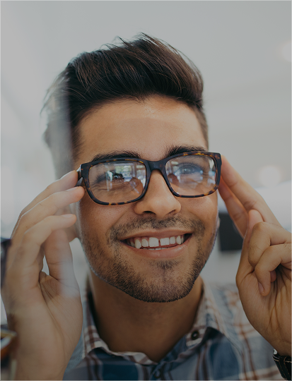 Young man smiling while trying on new glasses