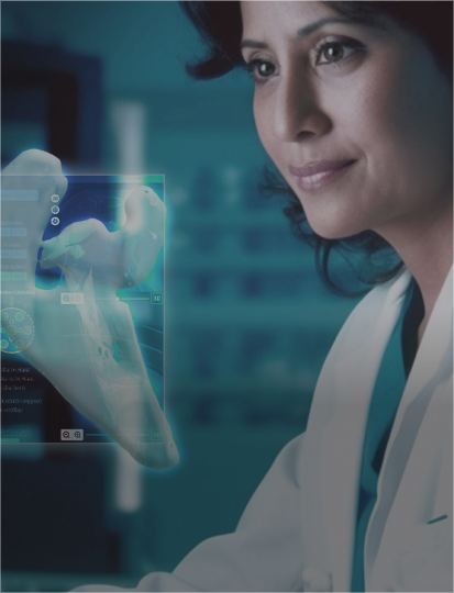 A woman in a lab coat analyzes information displayed on a screen in a research laboratory.