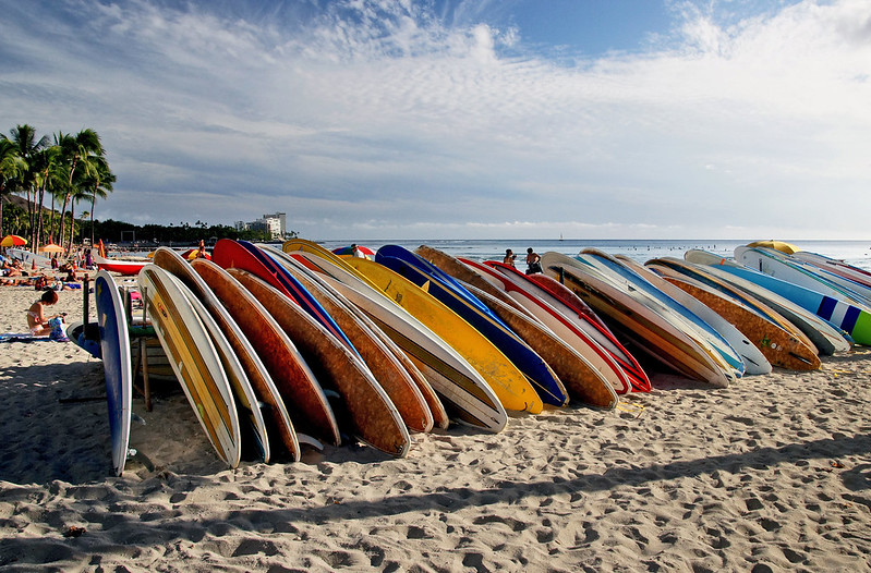 a stack of surfboards laying across a beach