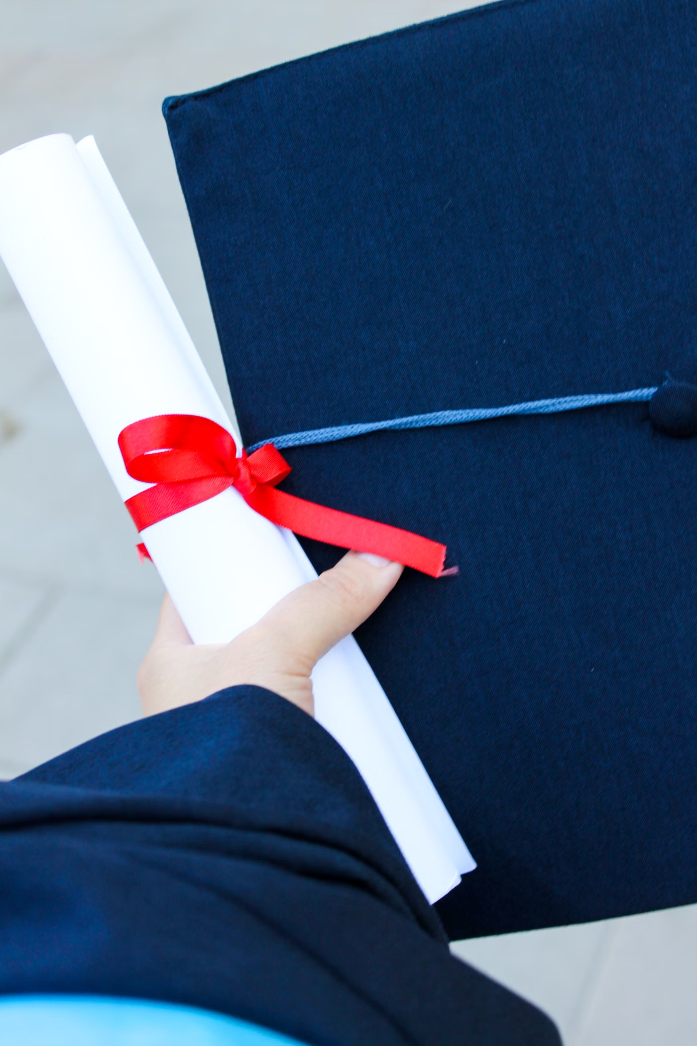 Graduate holding a diploma tied with a red ribbon