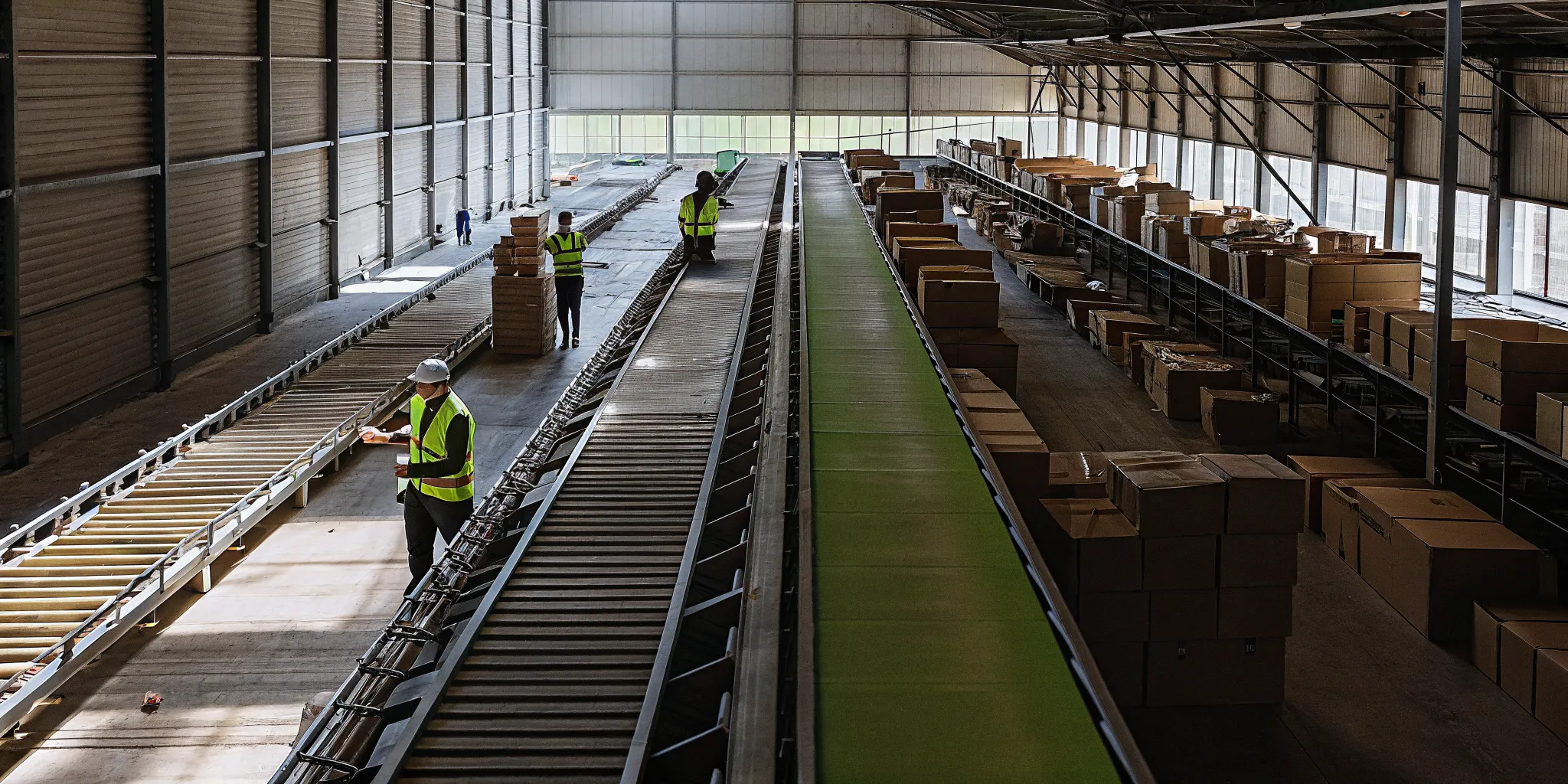 Workers and conveyors processing returned merchandise in a centralized returns hub warehouse