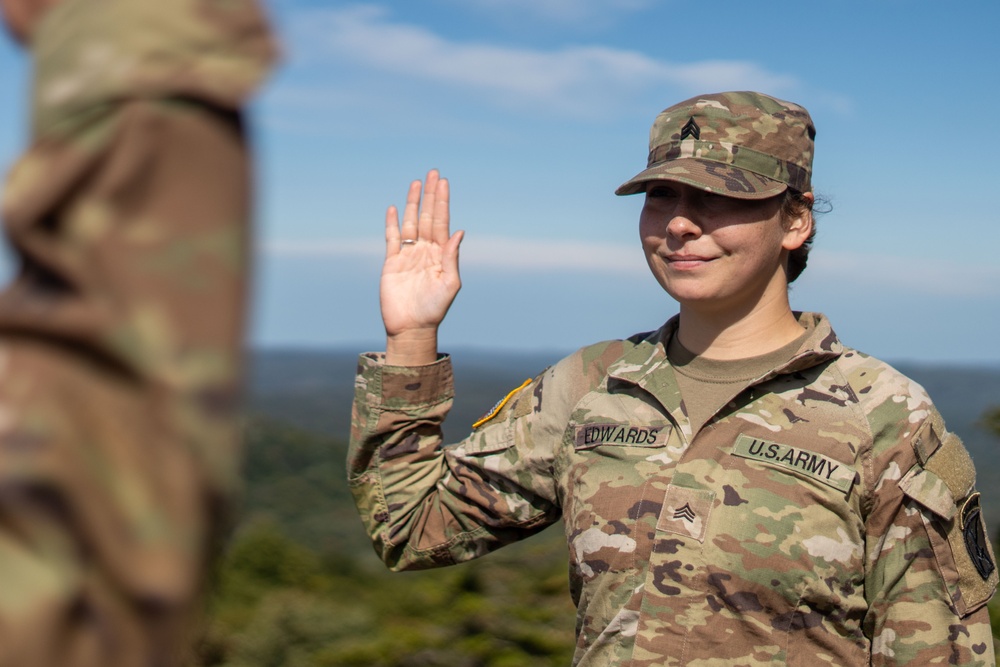 A soldier raises her right hand to reenlist on a mountaintop