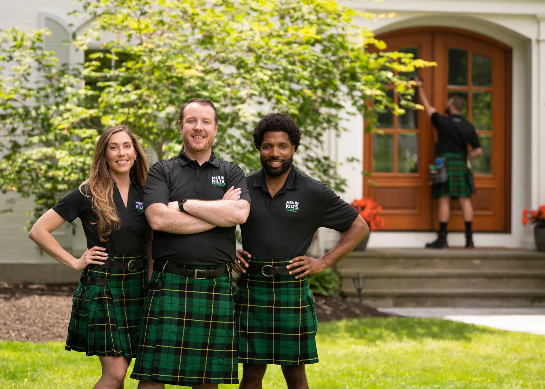 Men in Kilts team in branded shirts and green kilts outside a home