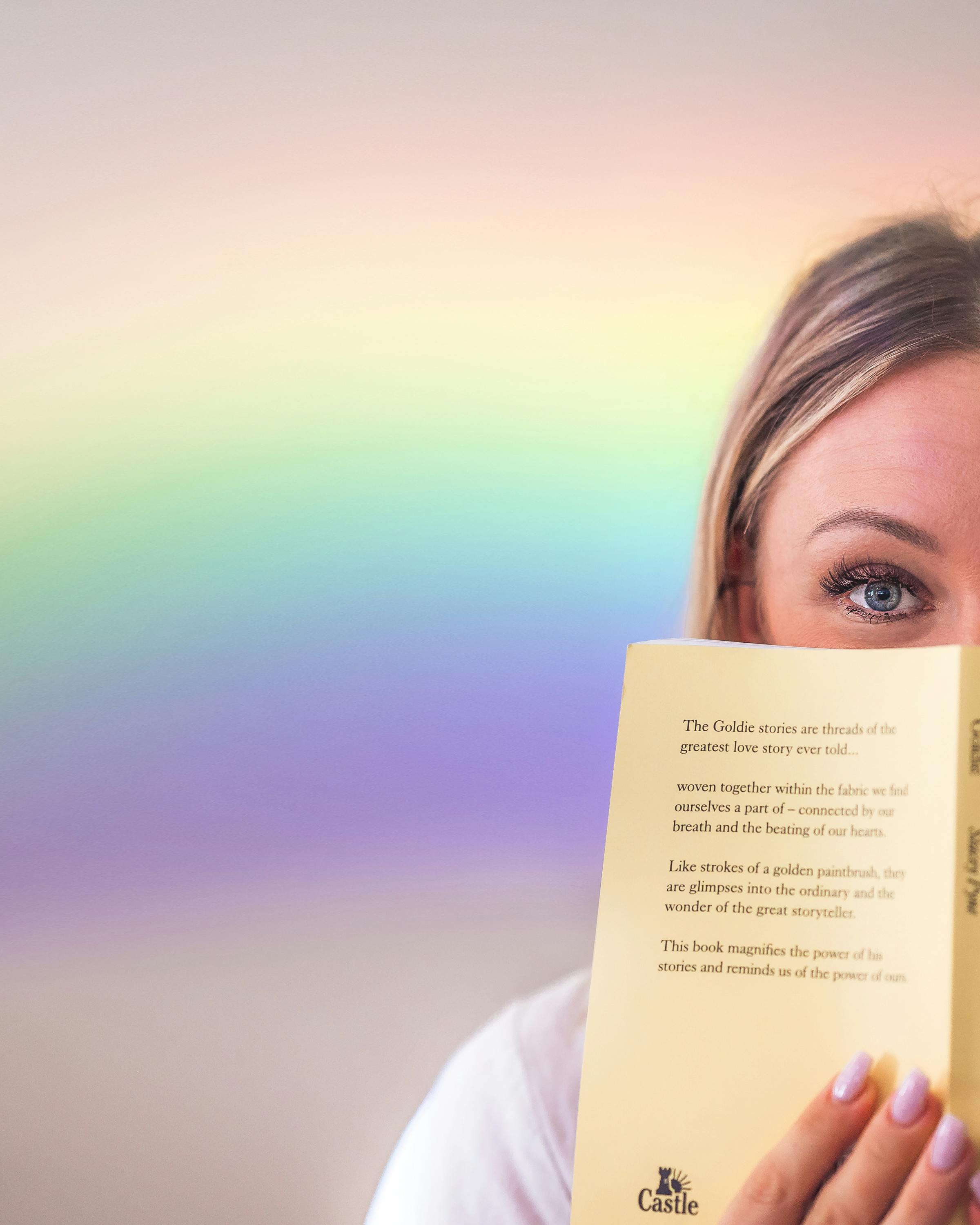 Person reading quietly as soft rainbow light filters across the page, symbolizing mindfulness and small moments of magic in everyday life.