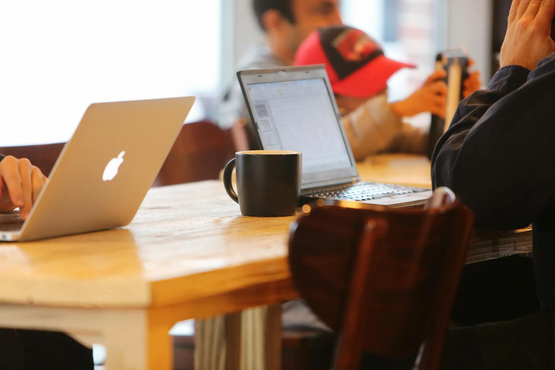 Two people sitting at a table with their laptops.