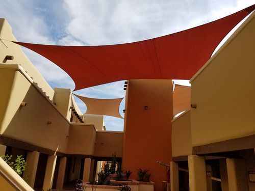 Red and orange sail shade installed above residential common area.